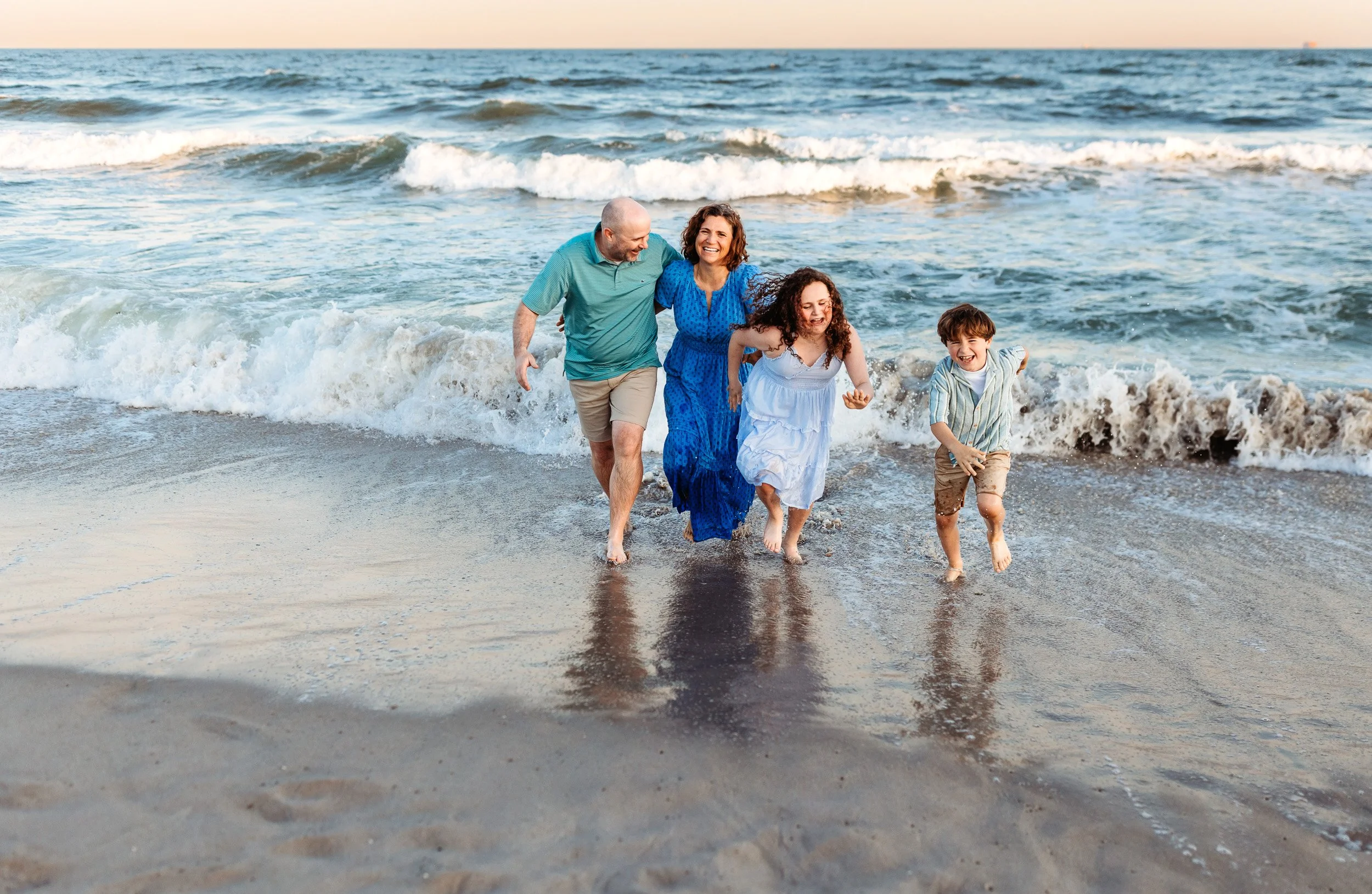 family running out of the ocean at sunset during family photos at the beach in Ponte vedra and they are laughing