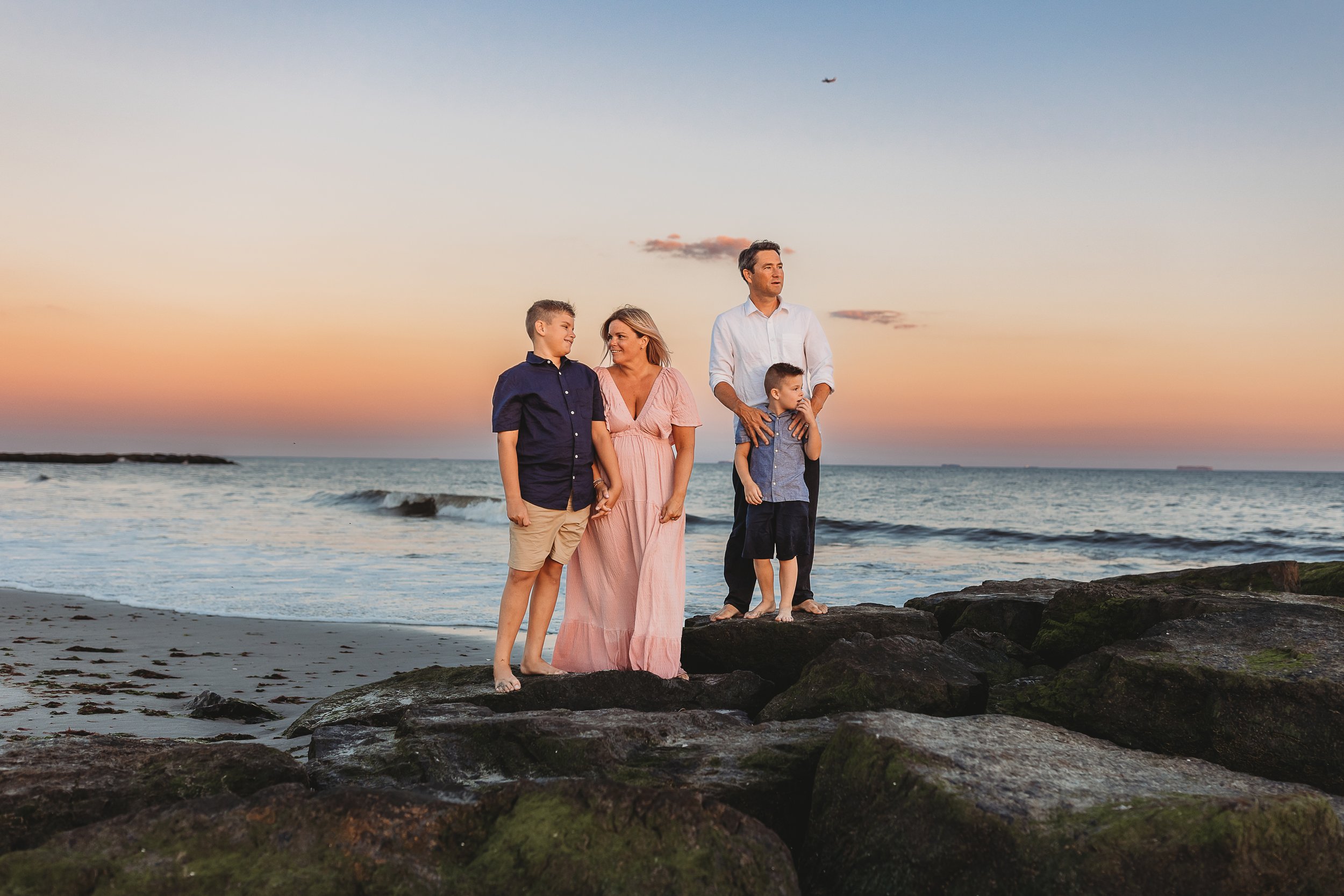 family on a jetty at the beach at sunset