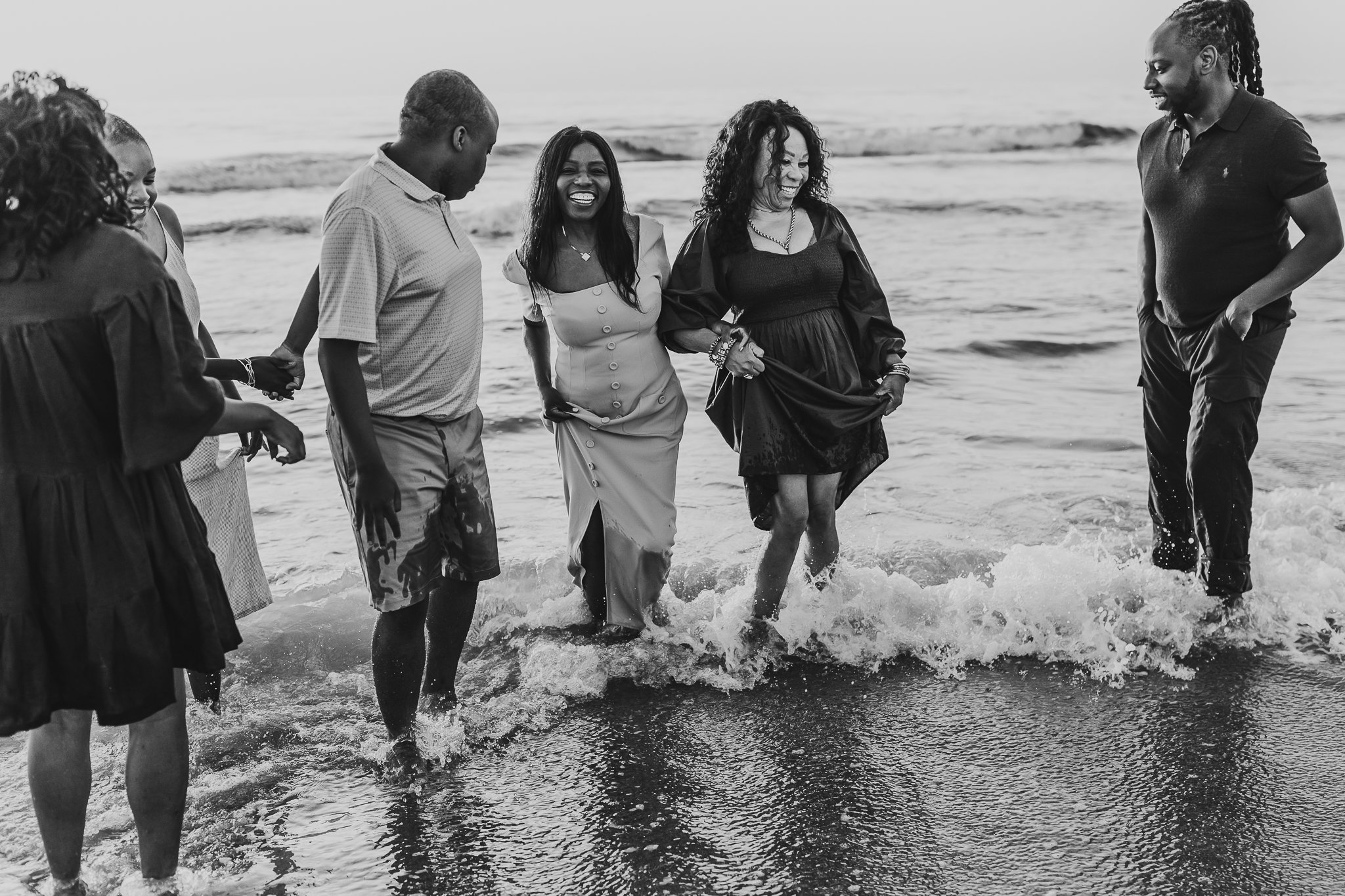 black and white image of a family playing in the ocean