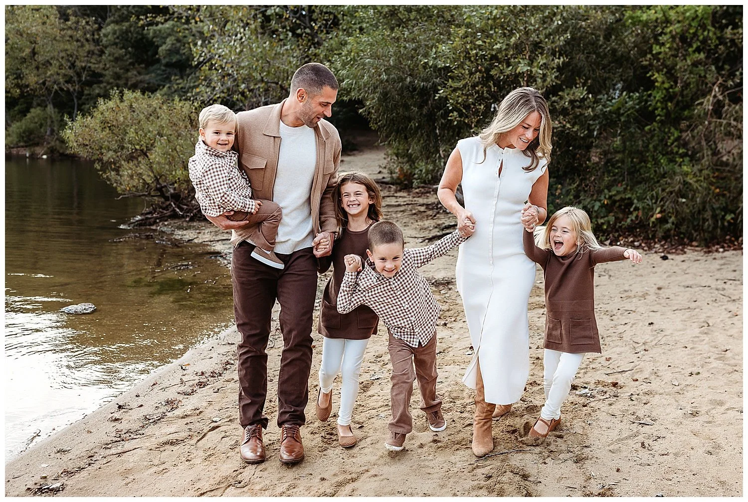 family walking holding hands along guana preserve and they are all laughing