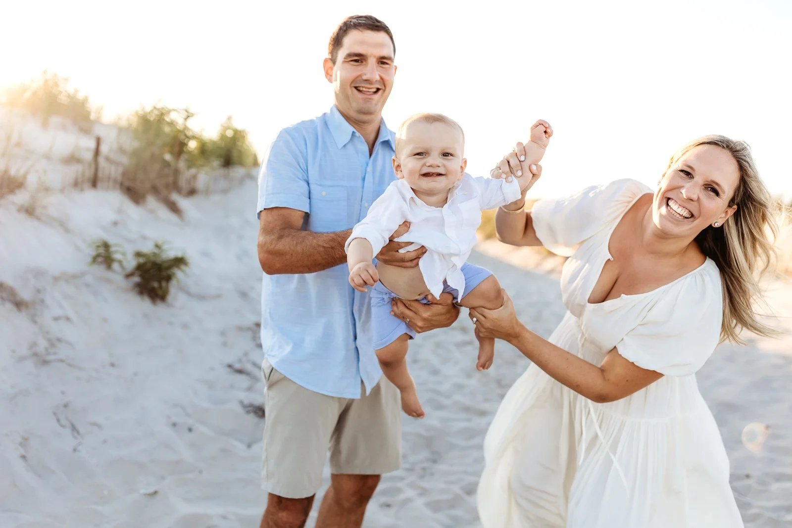 family airplane a baby boy and they are all laughing they are on the beach at sunset