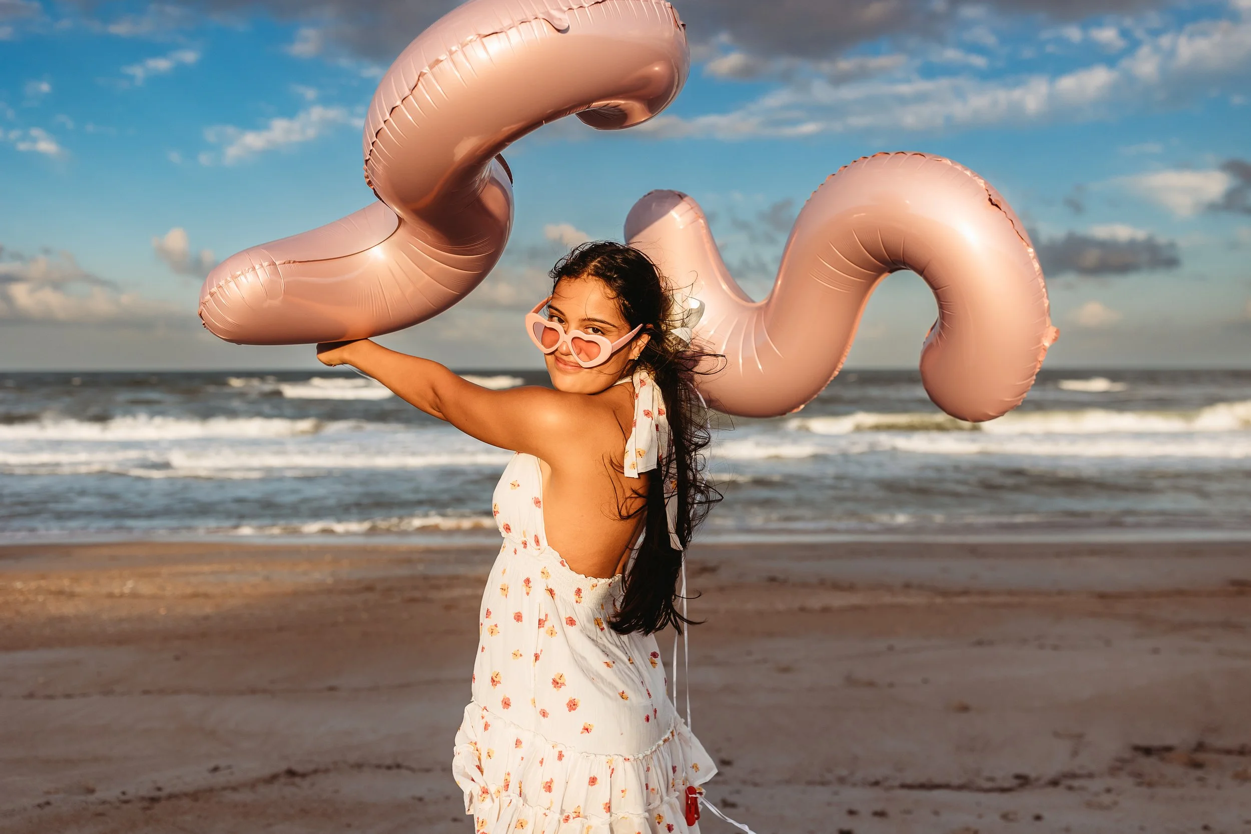 Young woman walking on the beach with number balloons during a Ponte Vedra portrait session