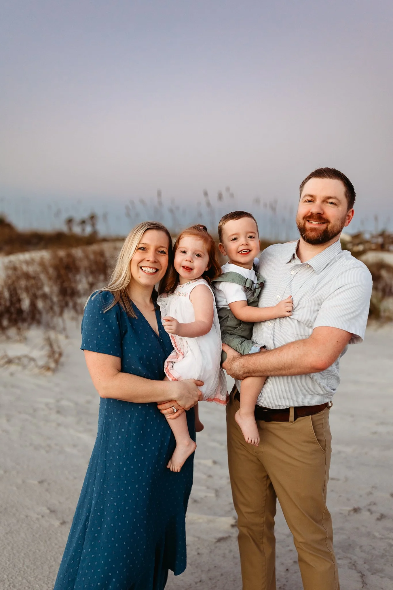 Family of four standing together on Crescent Beach during a relaxed sunrise family photo session near St. Augustine.