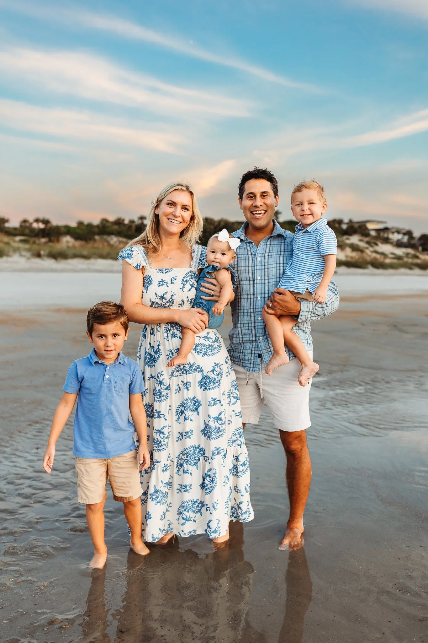 classic family portrait on th beach at sunrise with soft blue and pink sky in background