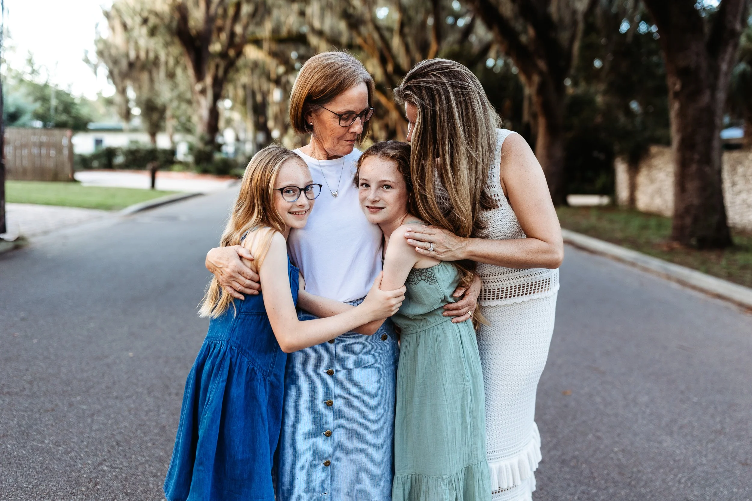 close up f grandma, her daughter and granddaughters embraced and laughing for candid family photos