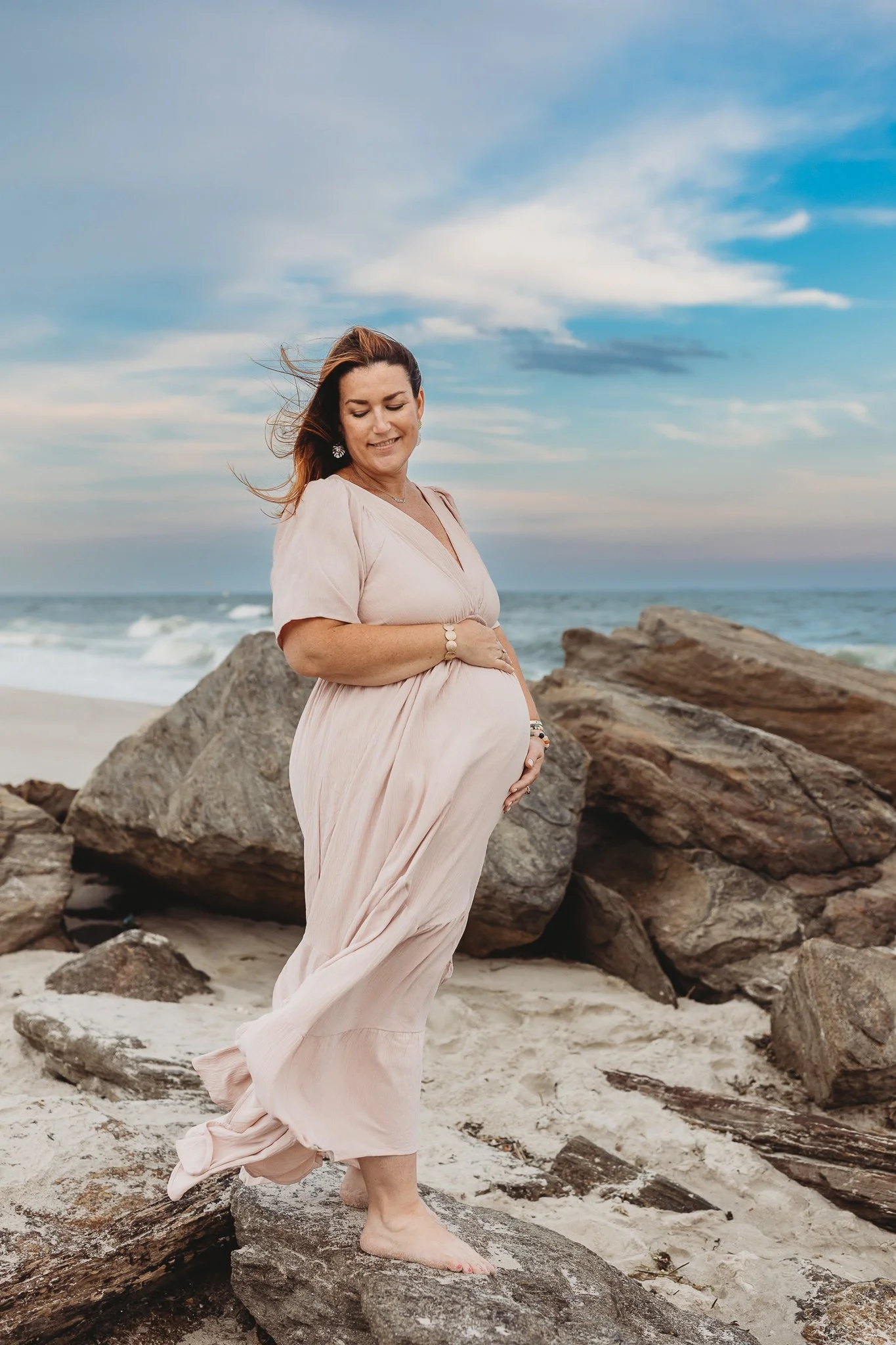 mom in pink gauze dress for maternity photos on Neptune beach
