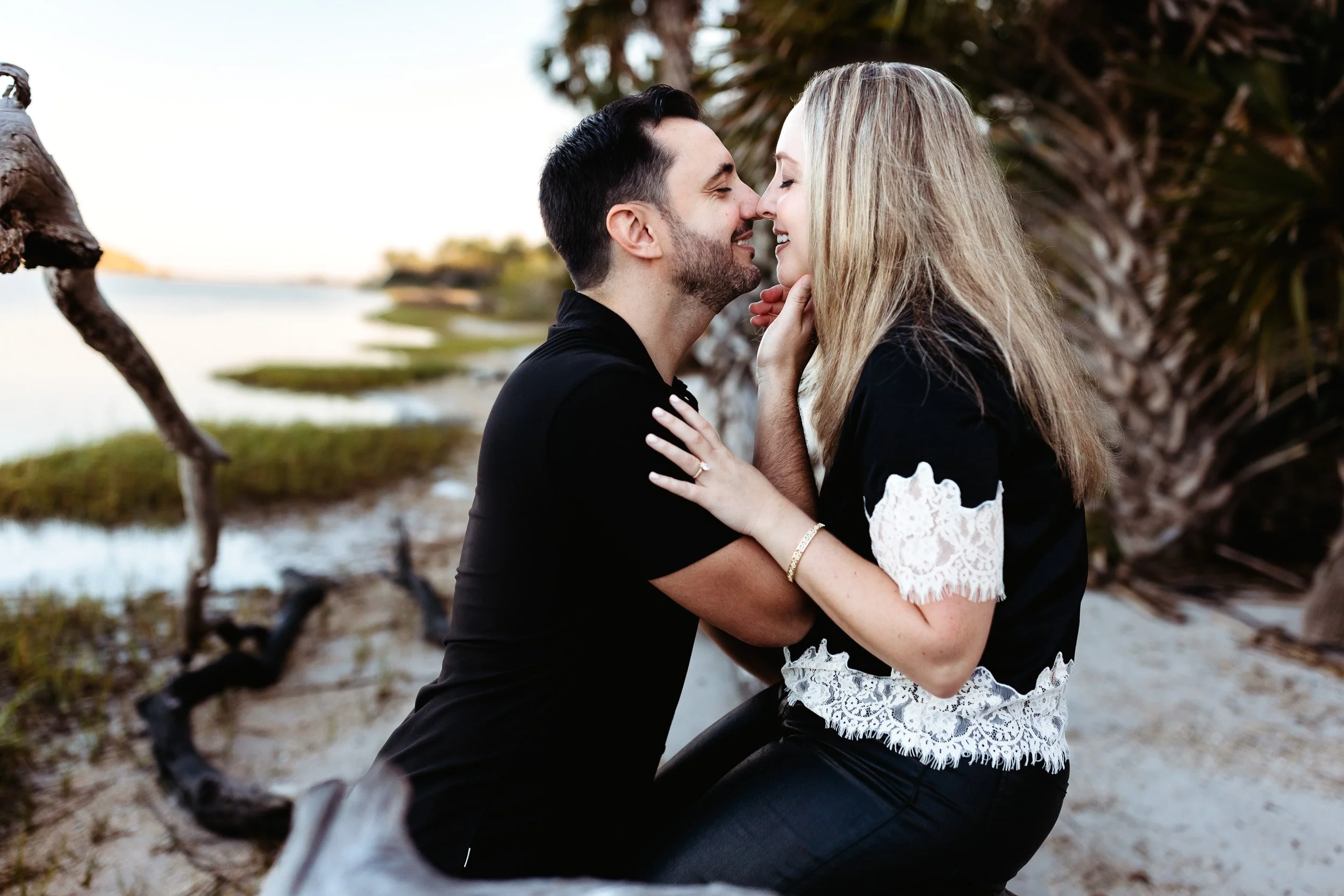 couple about to kiss while seated on the intracoastal after getting engaged