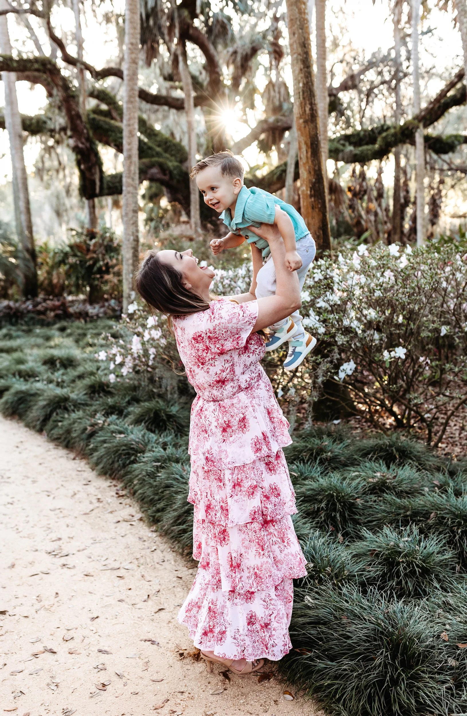 mother lifting her little boy in the air at sunset and he is laughing