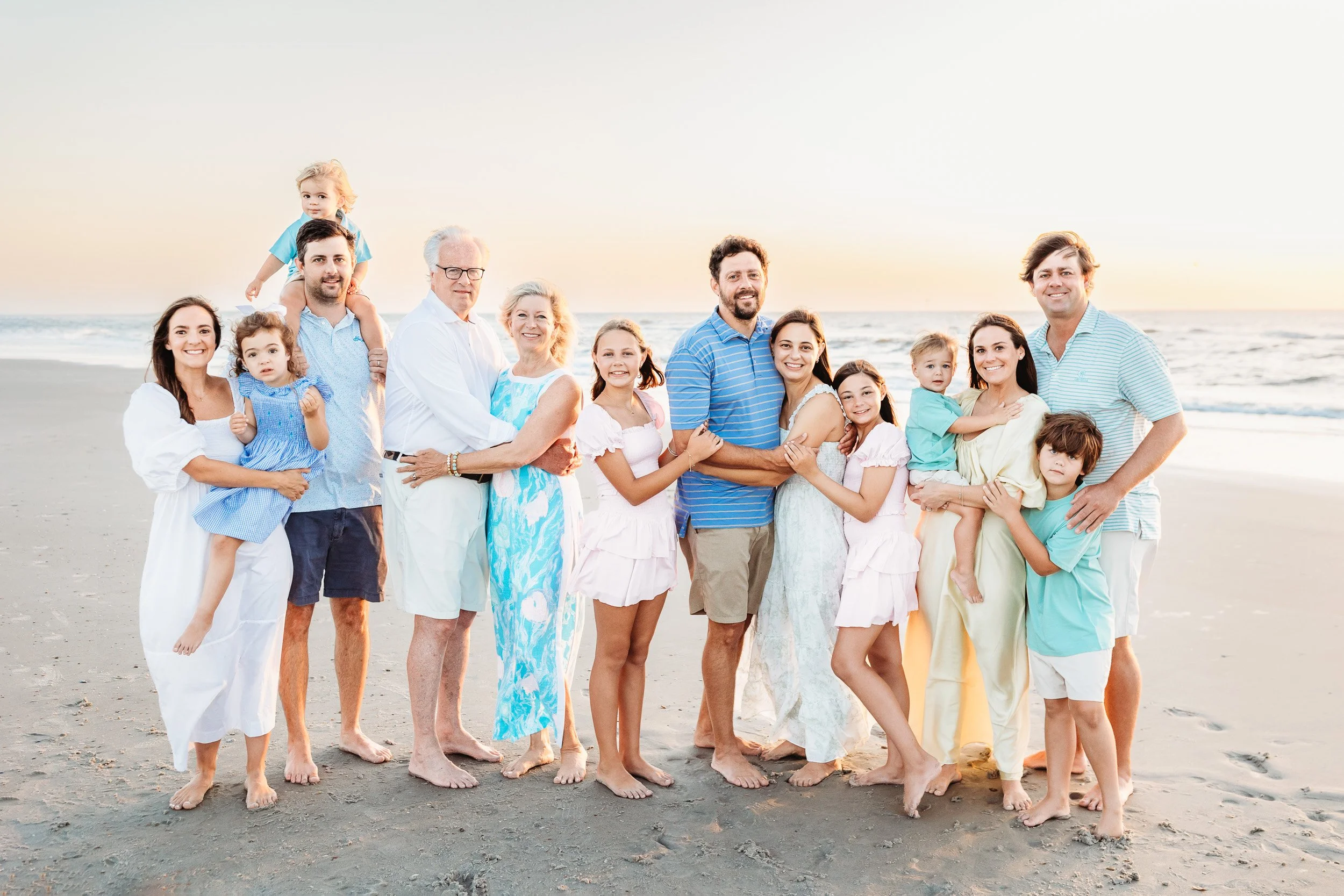 large family each embraced with children for a family portrait on the beach at sunrise