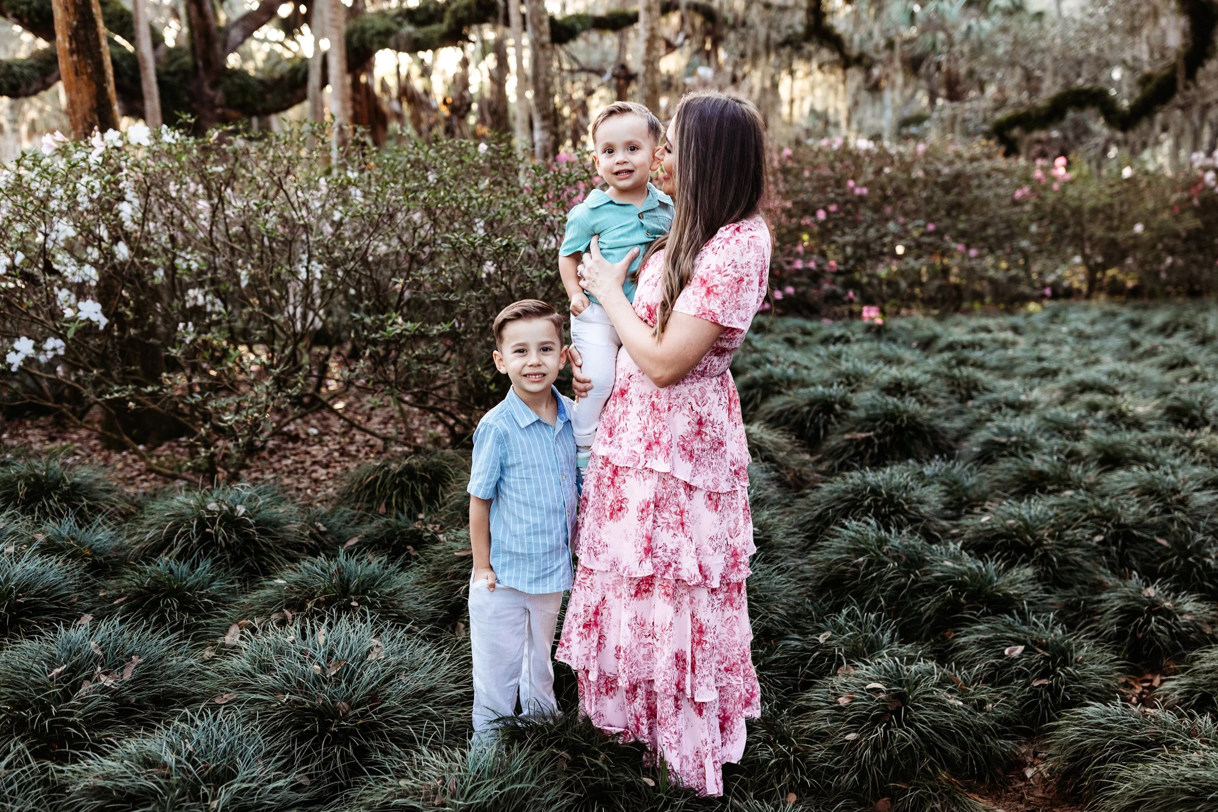 a mother in pink holding her boys and they are laughing