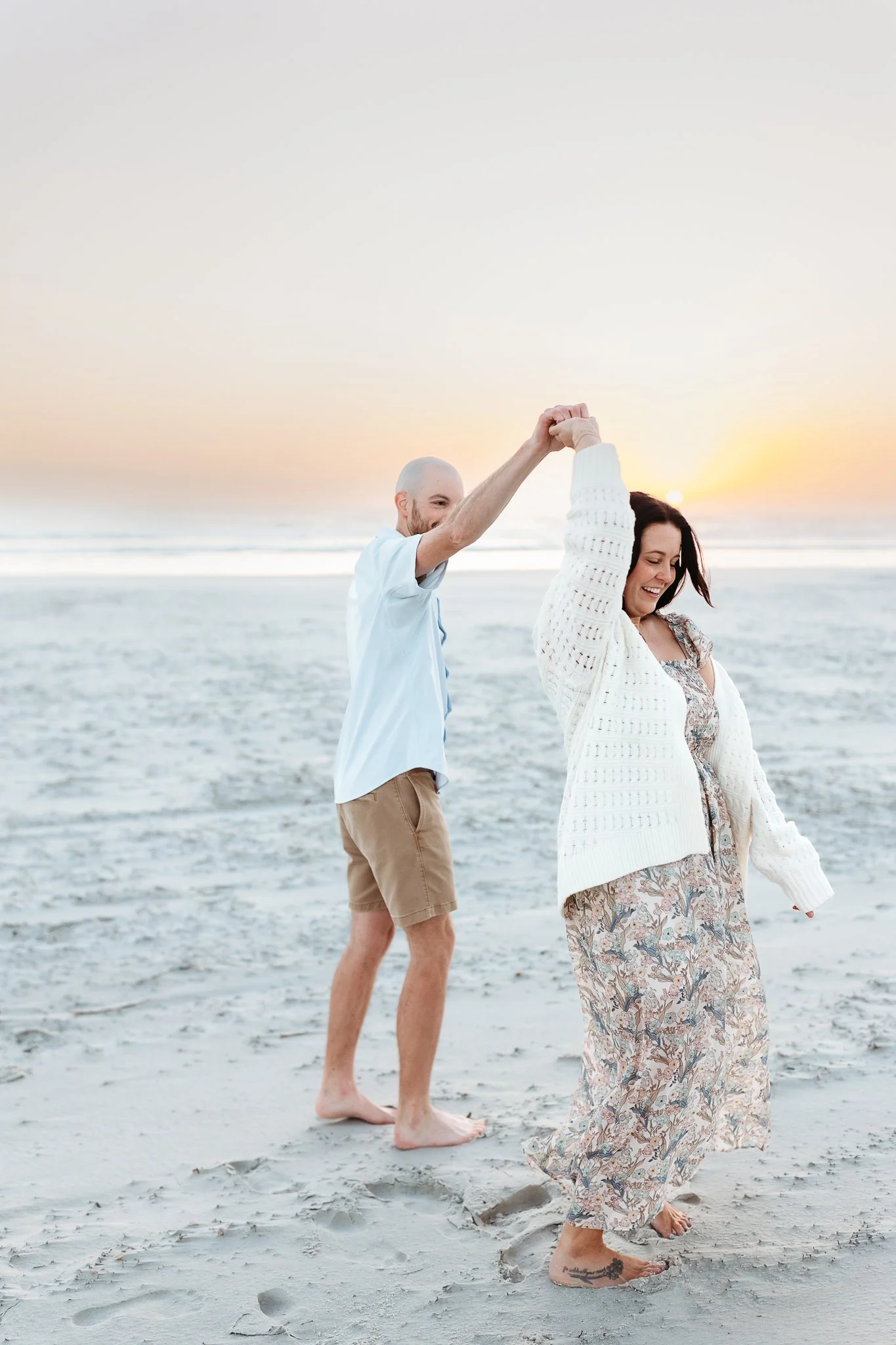 Couple twirling together on the sand during a sunrise beach photography session in Crescent Beach, Florida.
