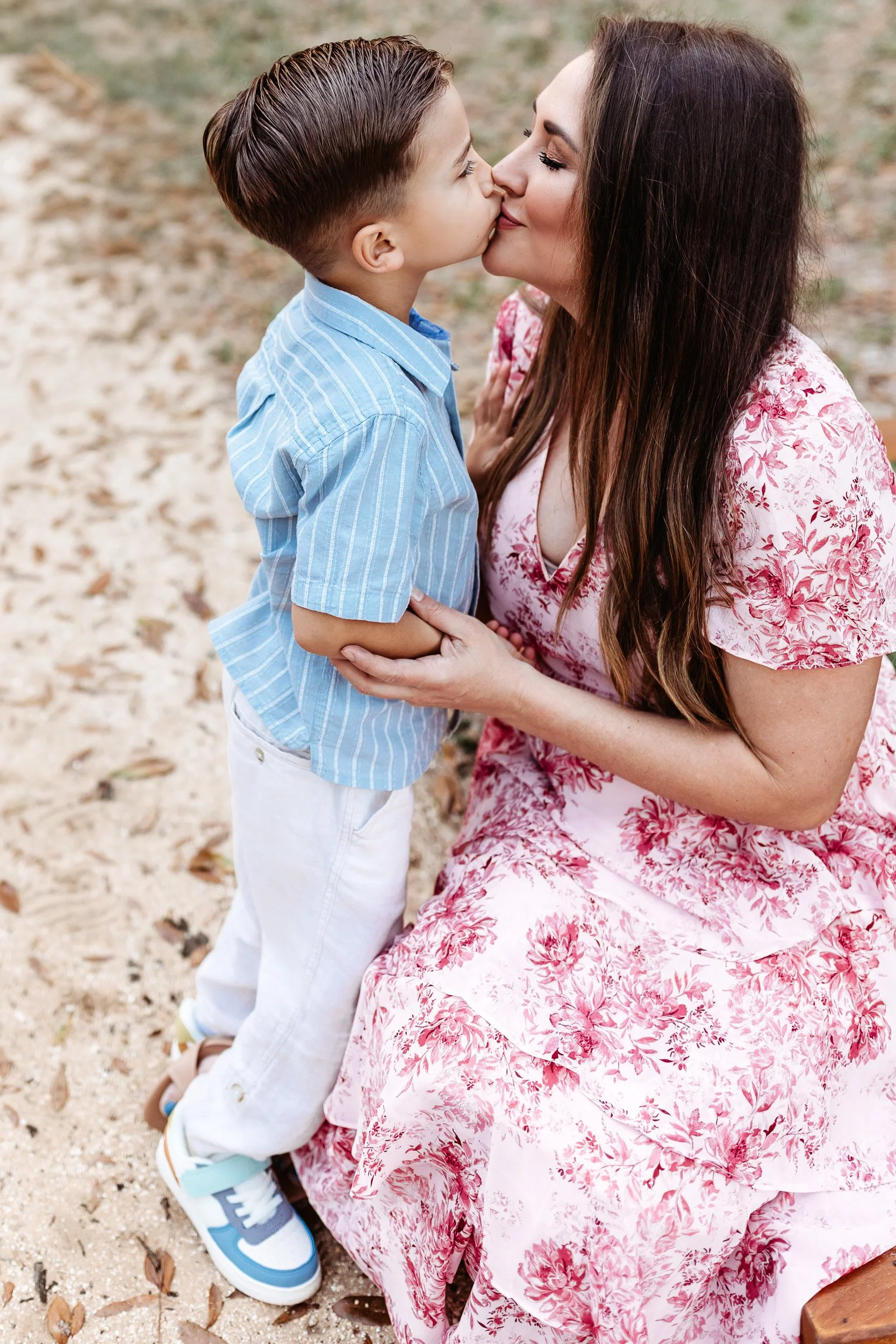 mother kissing her son at a garden