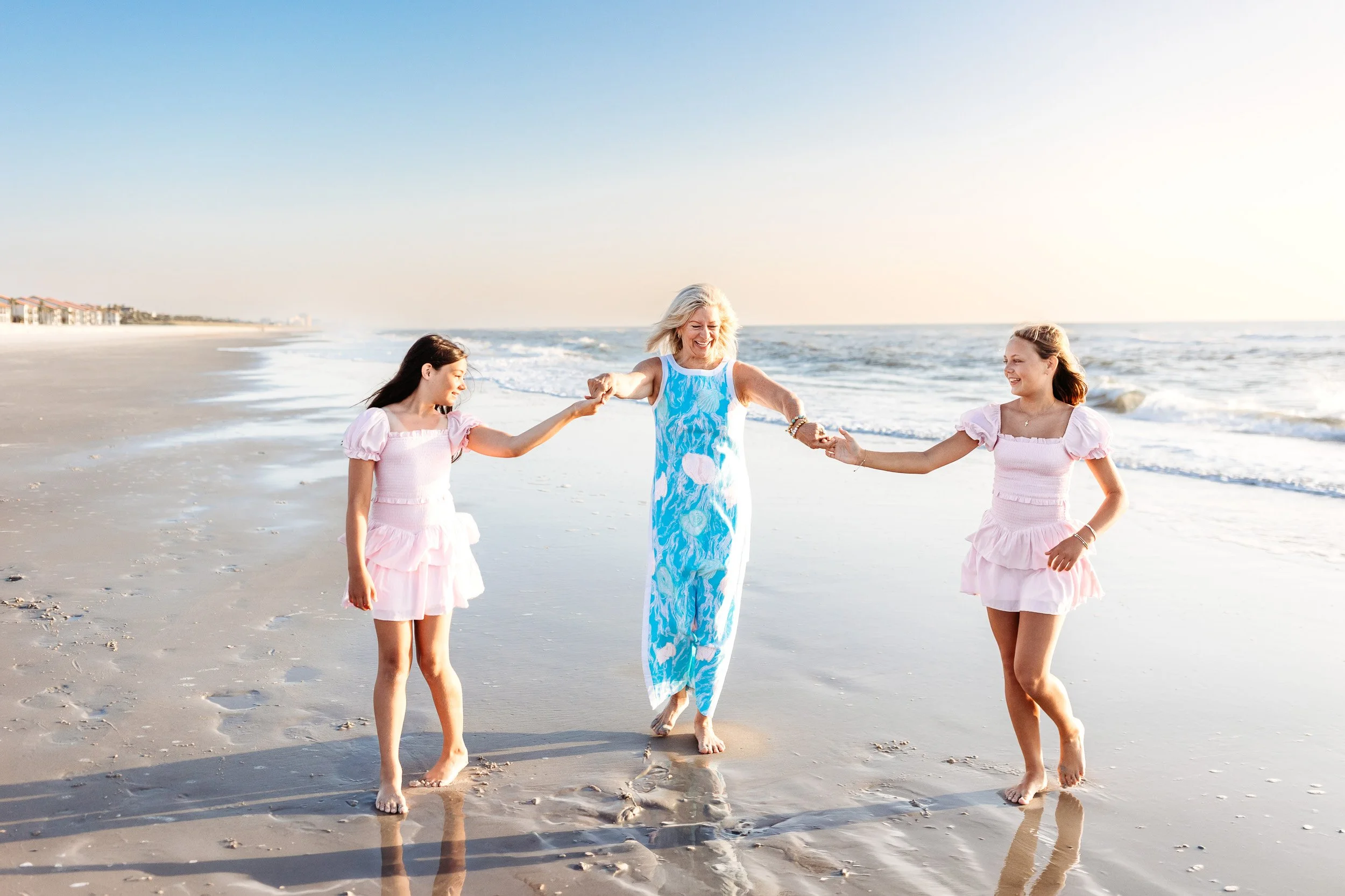 grandma dancing with her tween granddaughters at sunrise on the beach and they are all laughing