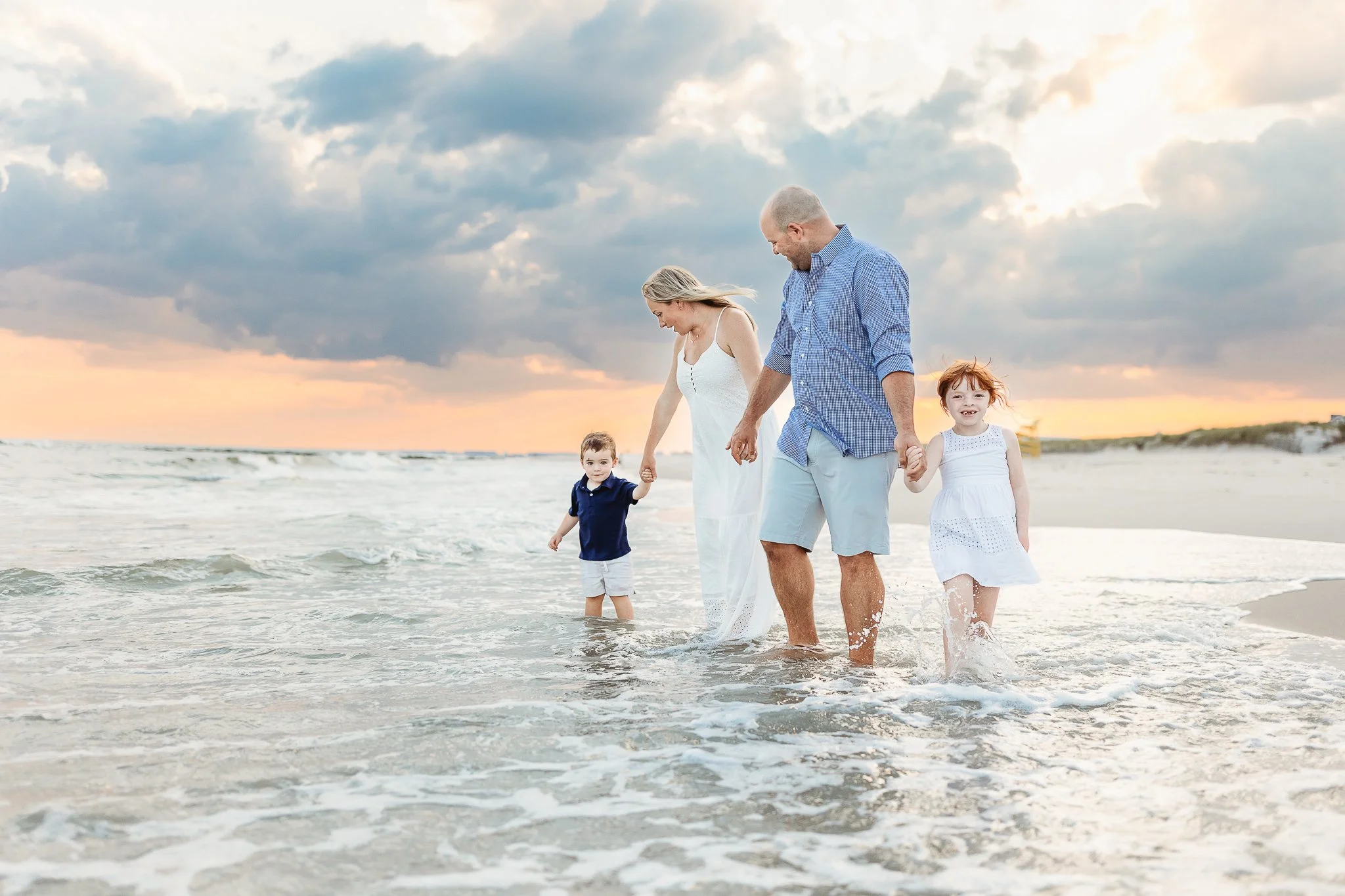 family walking in the water of the ocean at sunset during a family photo session