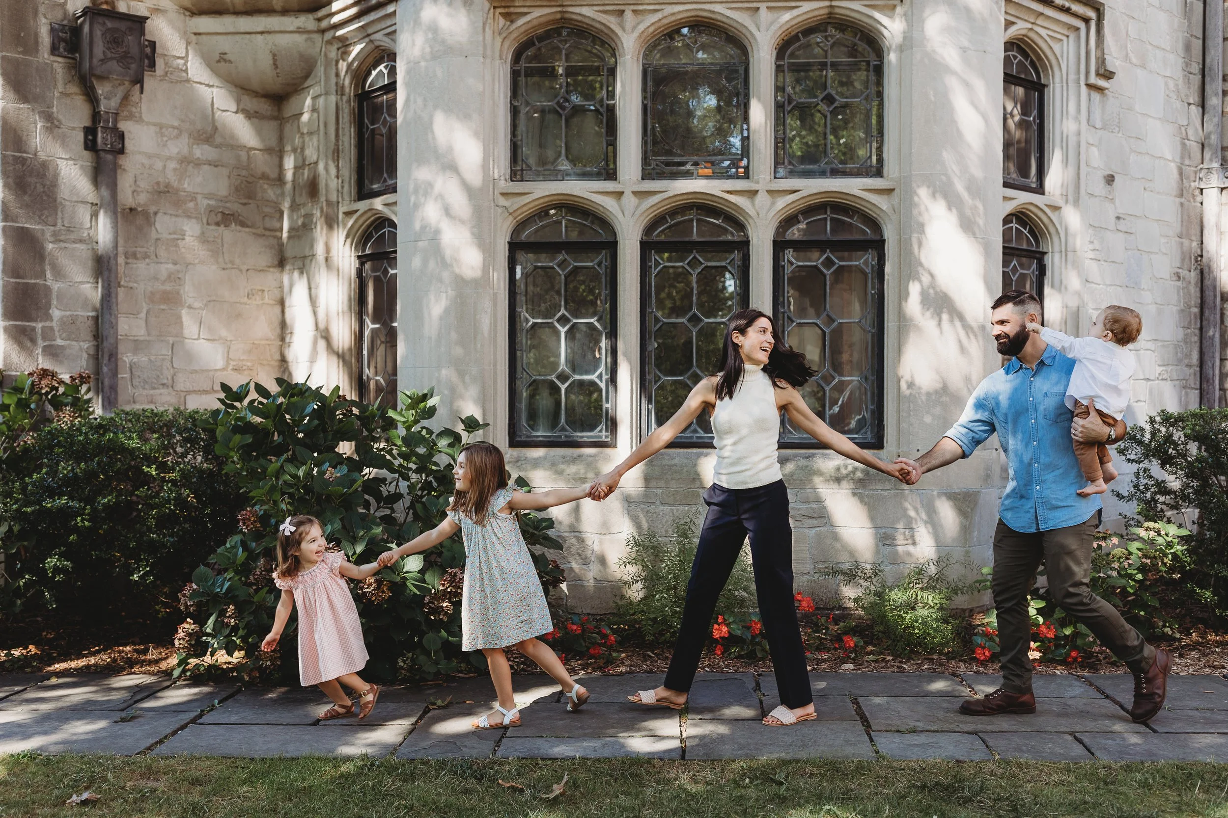 family holding hands walking in front of a historic building laughing