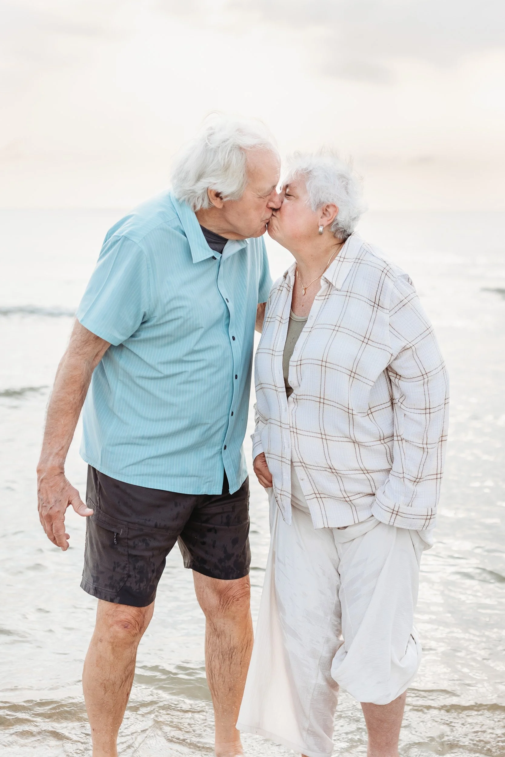 grandparents kissing in the ocean at sunrise during a family photo session in st augustine