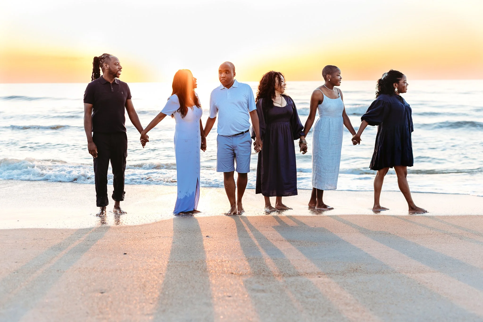family standing together naturally on the beach in soft early morning light