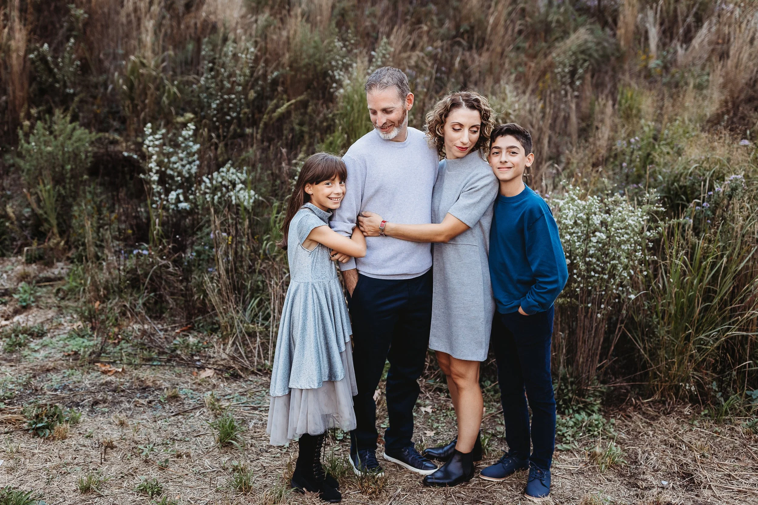 family embraced in front of wildflowers for family photos