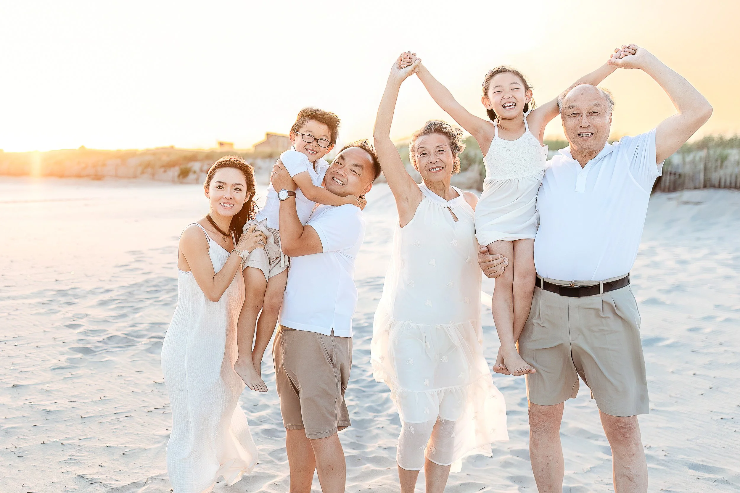 fun family photo of parents and grandparents holding twin toddlers and they are lifting them up while holding their hands.  They are on St Augustine beach at sunset 