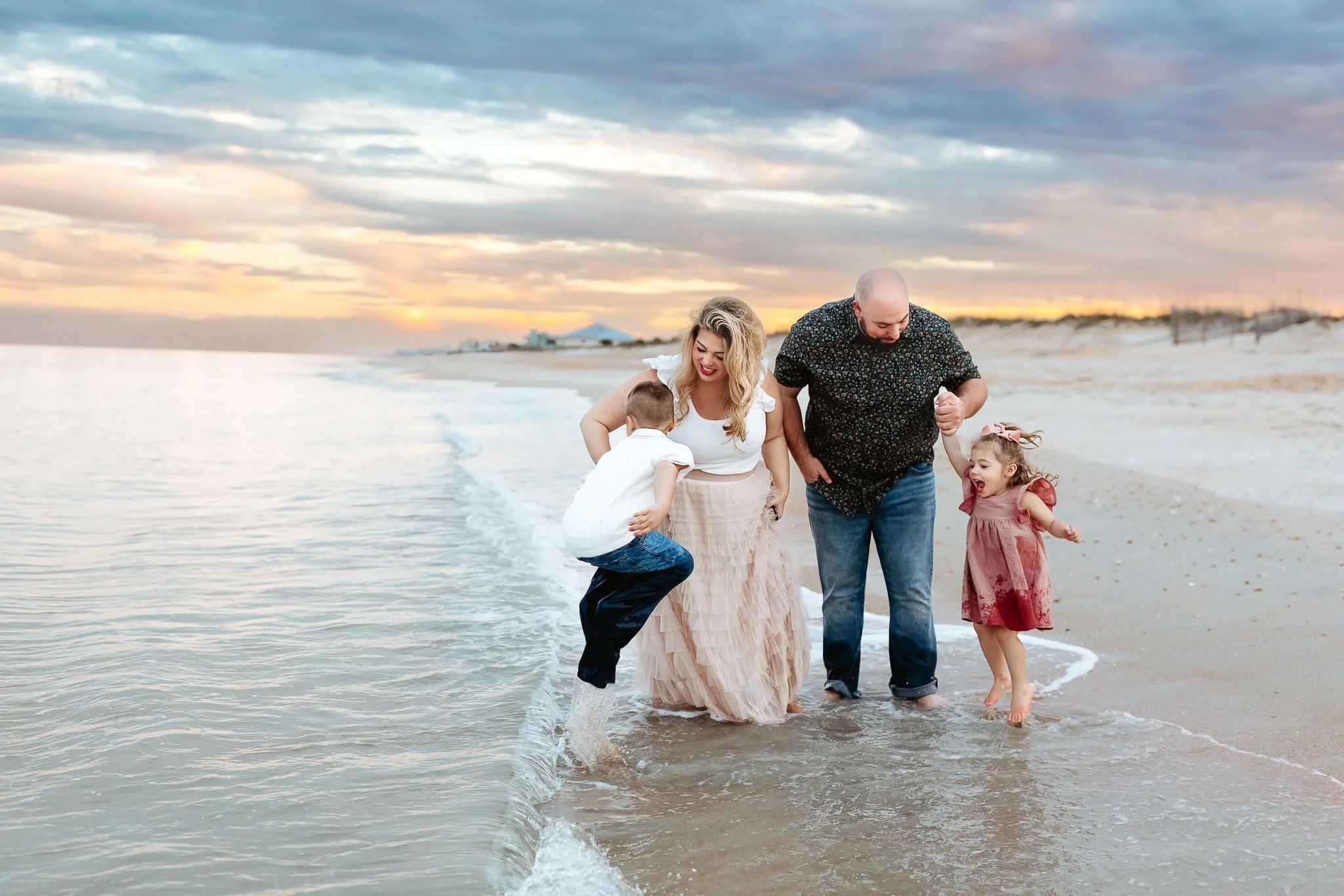 family playing in the ocean at sunset