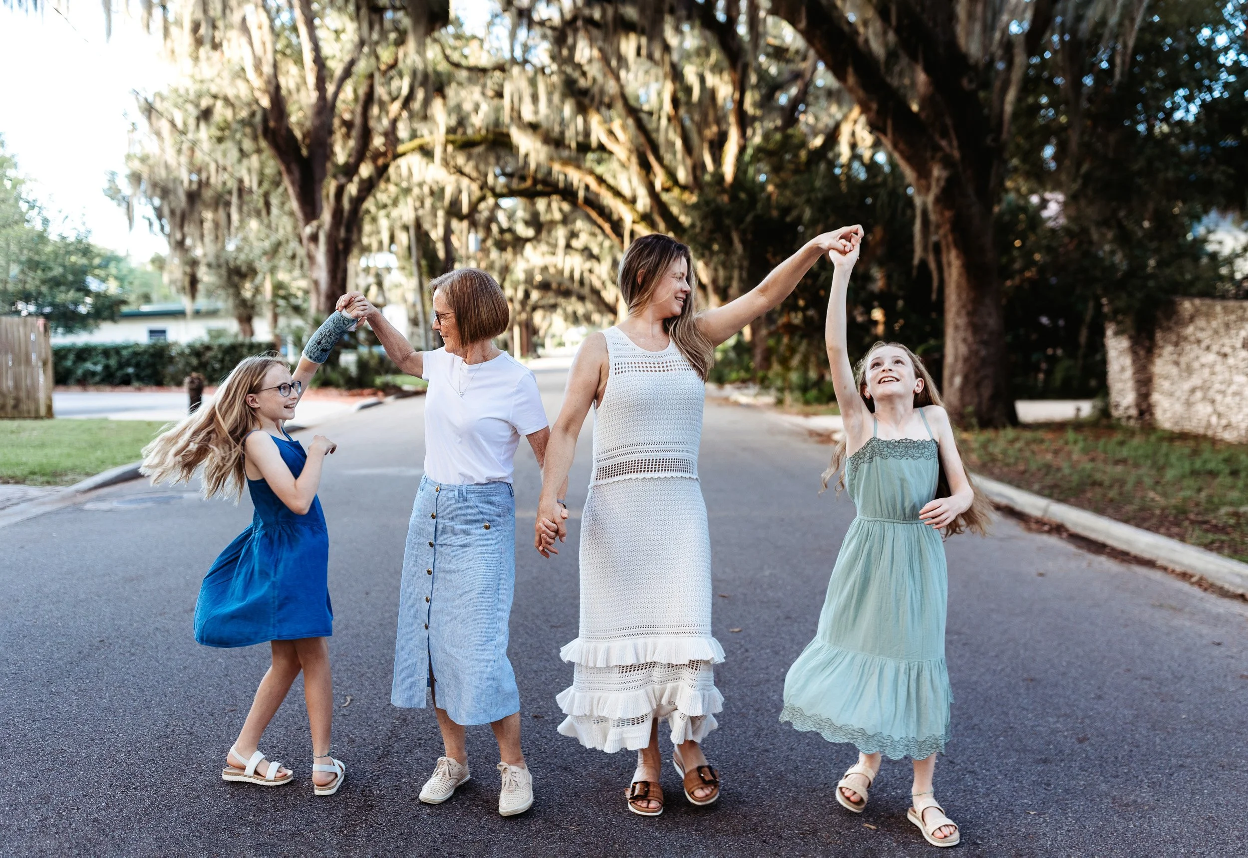 mother and grandma twirling twin girls at sunset on a street in st augustine