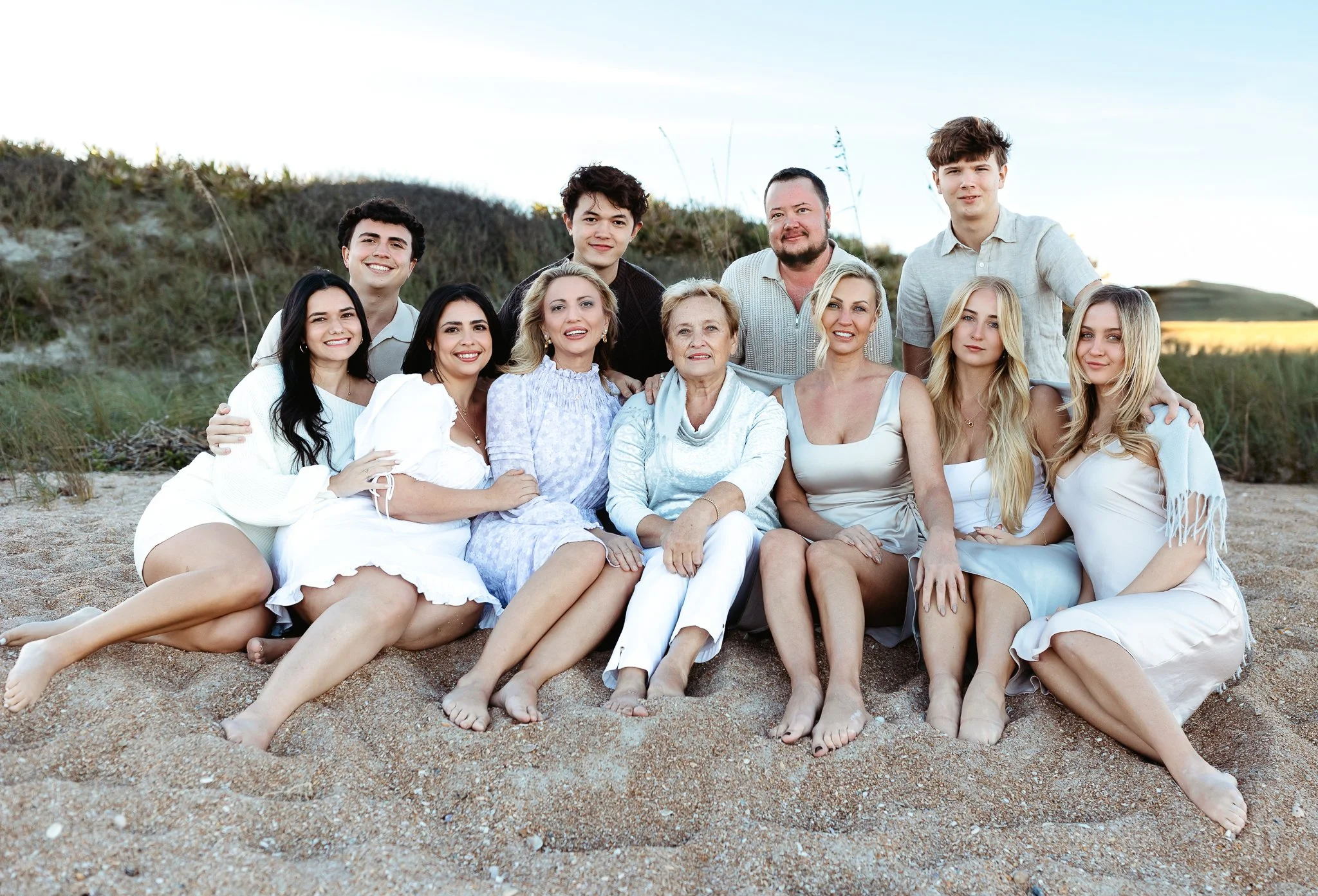 family seated on the sand at guana preserve at sunset for a large group family portrait