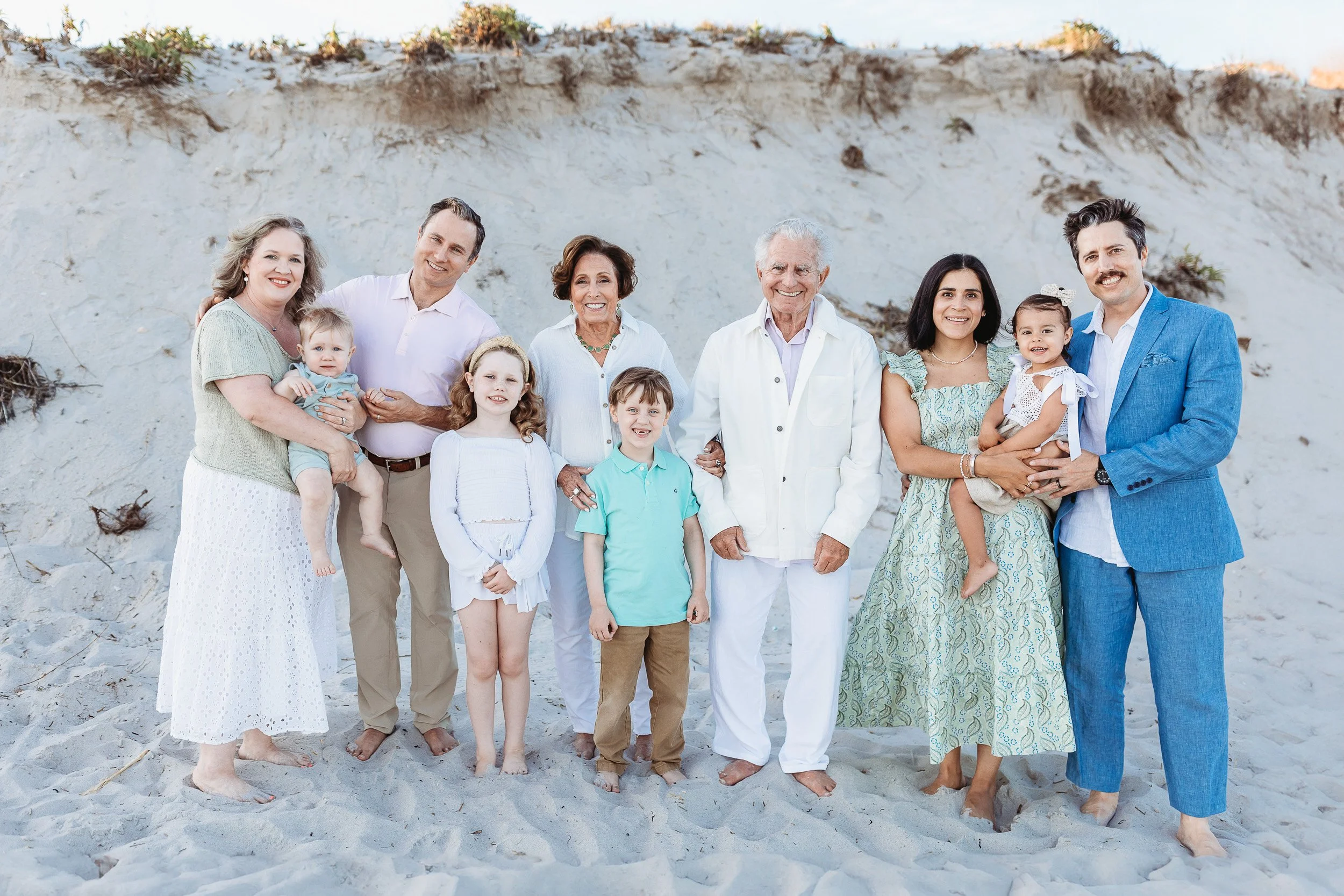 family portrait in front of a dune at sunset.  Family wearing green and blue and they are in St augustine on the beach 