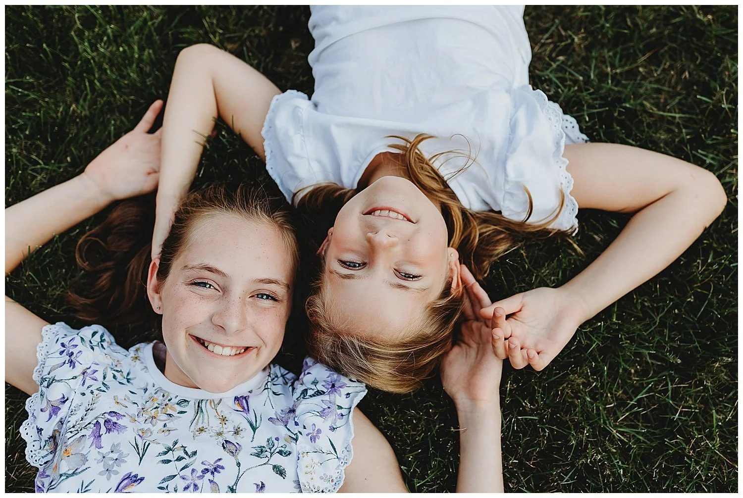 Close up of sisters laying together in the grass during a relaxed family photography session
