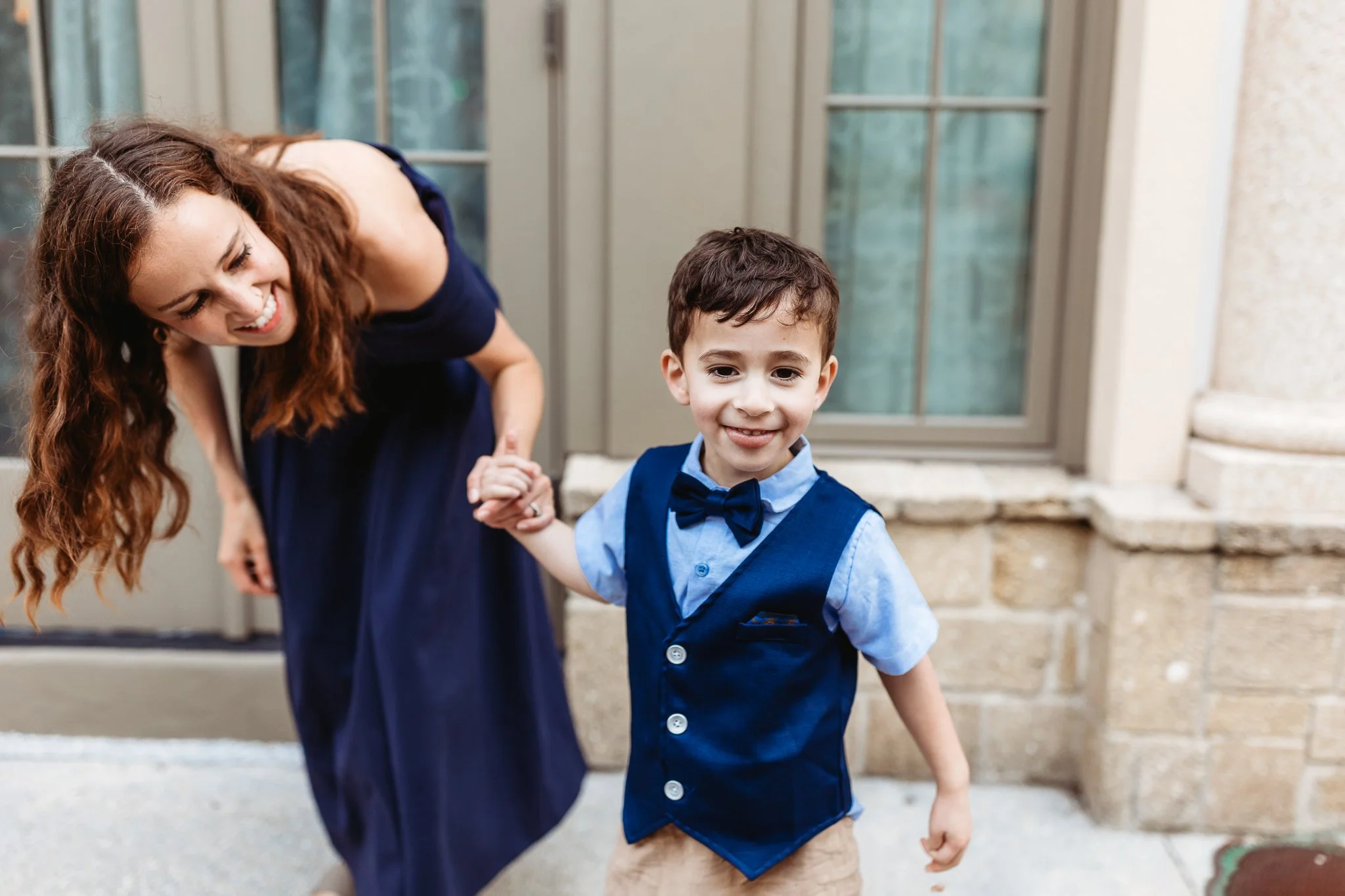 mother and child holding hands and laughing on the cobblestone streets