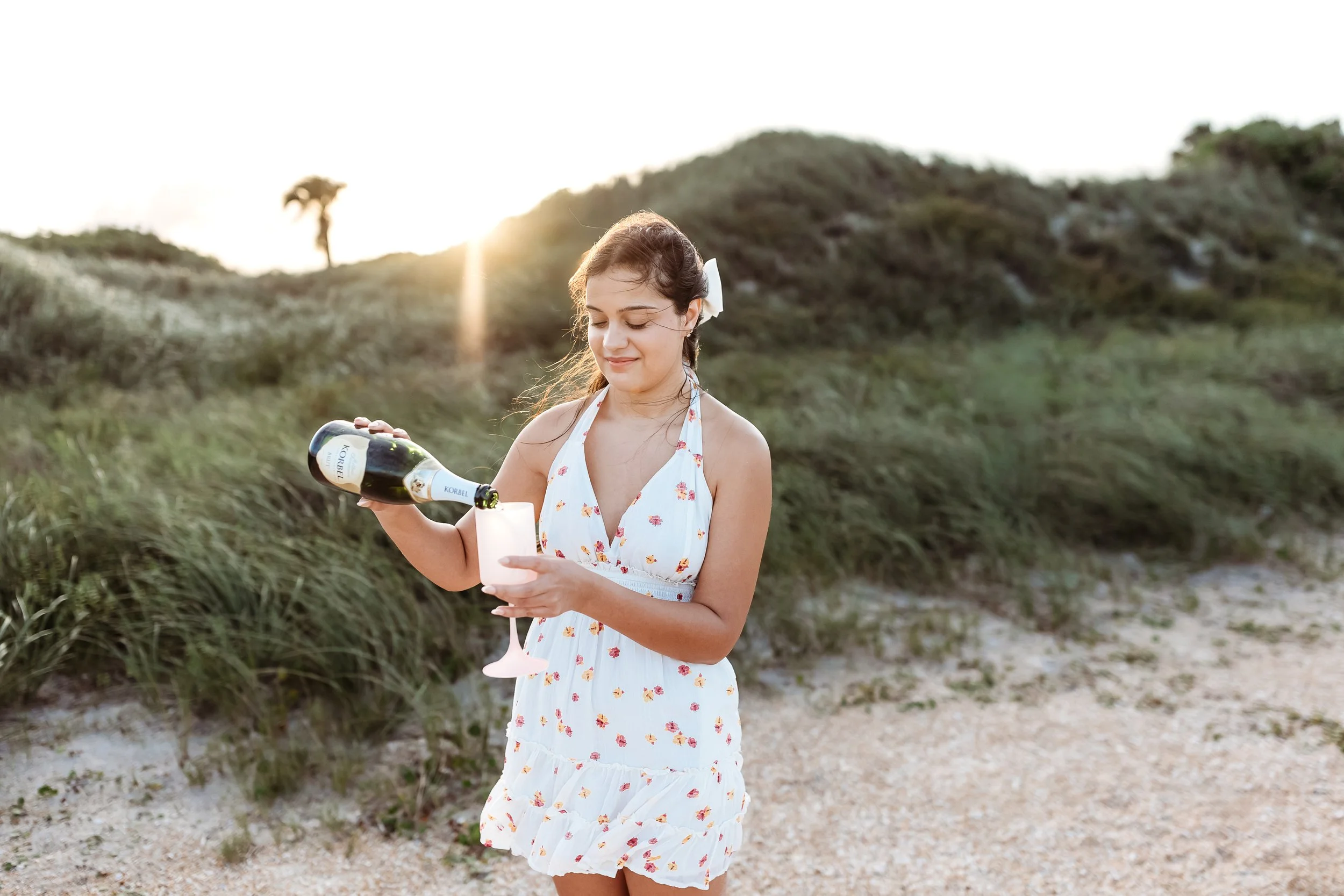 Young woman laughing during a celebratory champagne pop on the beach