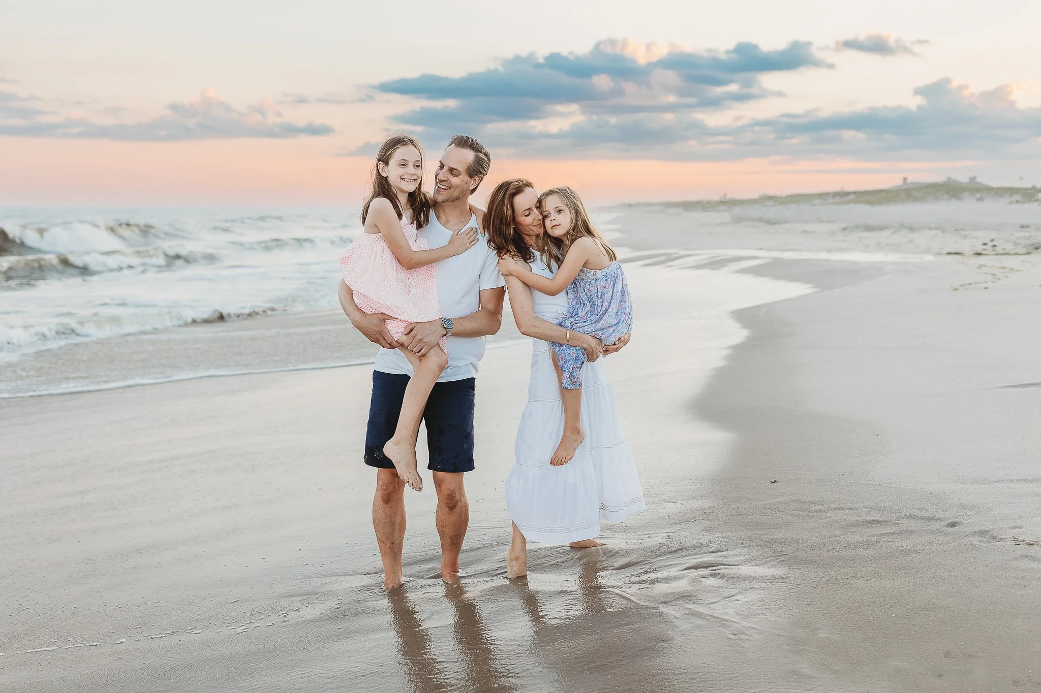 family in the ocean at sunset embraced and laughing