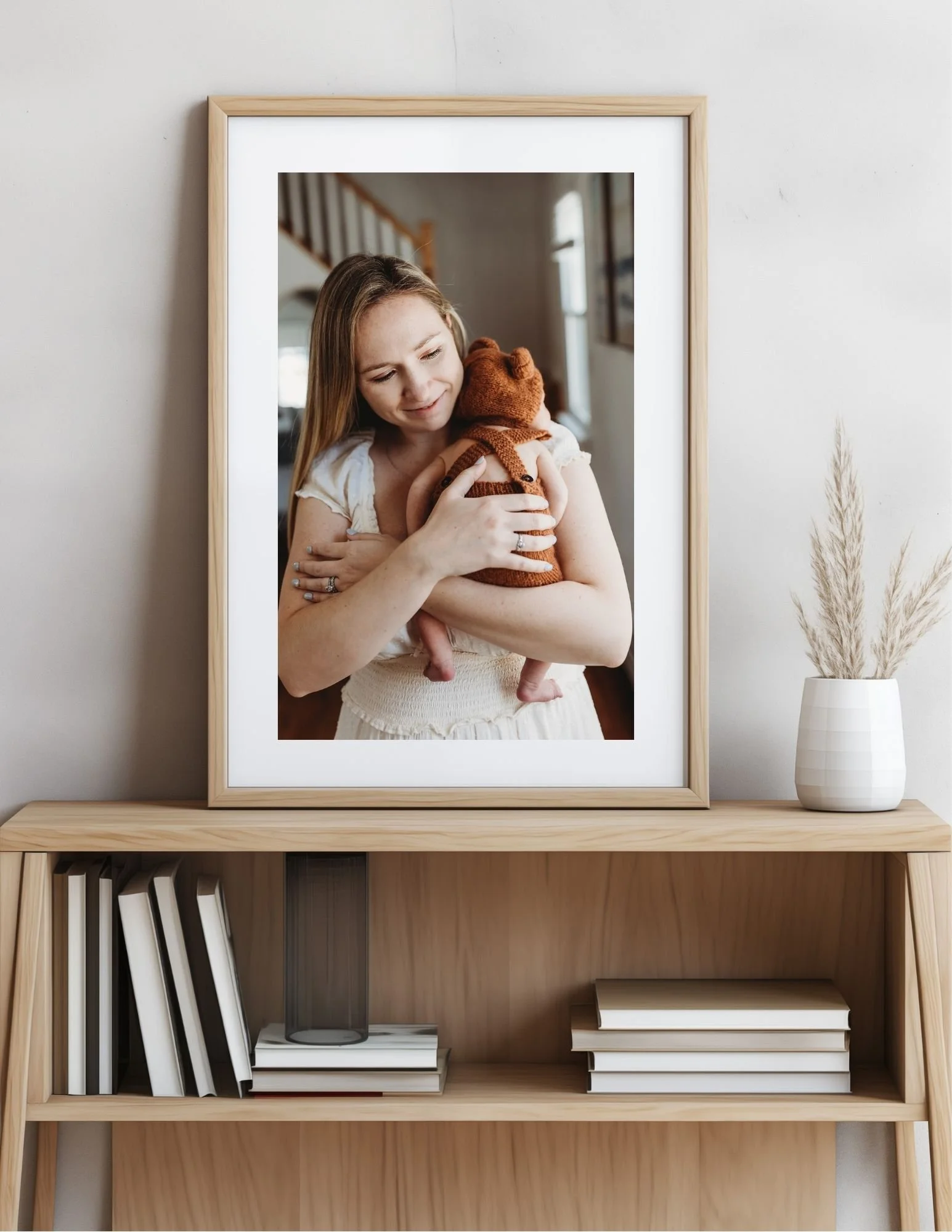 large image of a woman holding her baby closely and It is on a hallway table and the image was from a Jacksonville in home newborn session