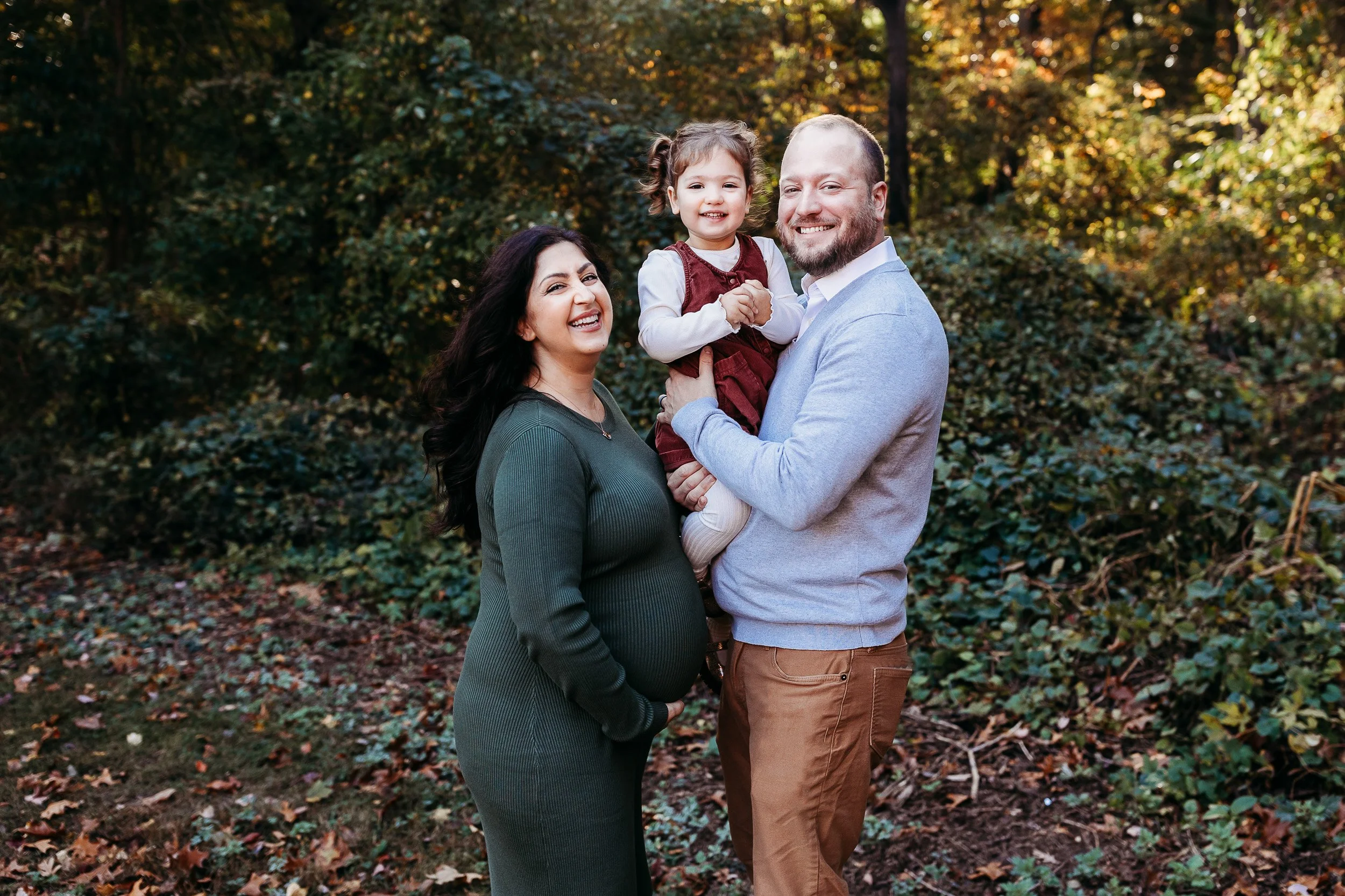 family in fall clothing laughing at the camera 