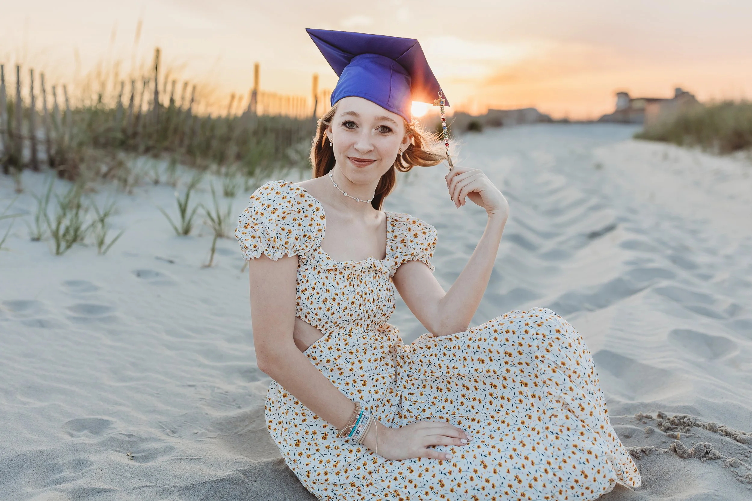 graduate on Neptune beach with cap on and urban outfitters dress at sunset