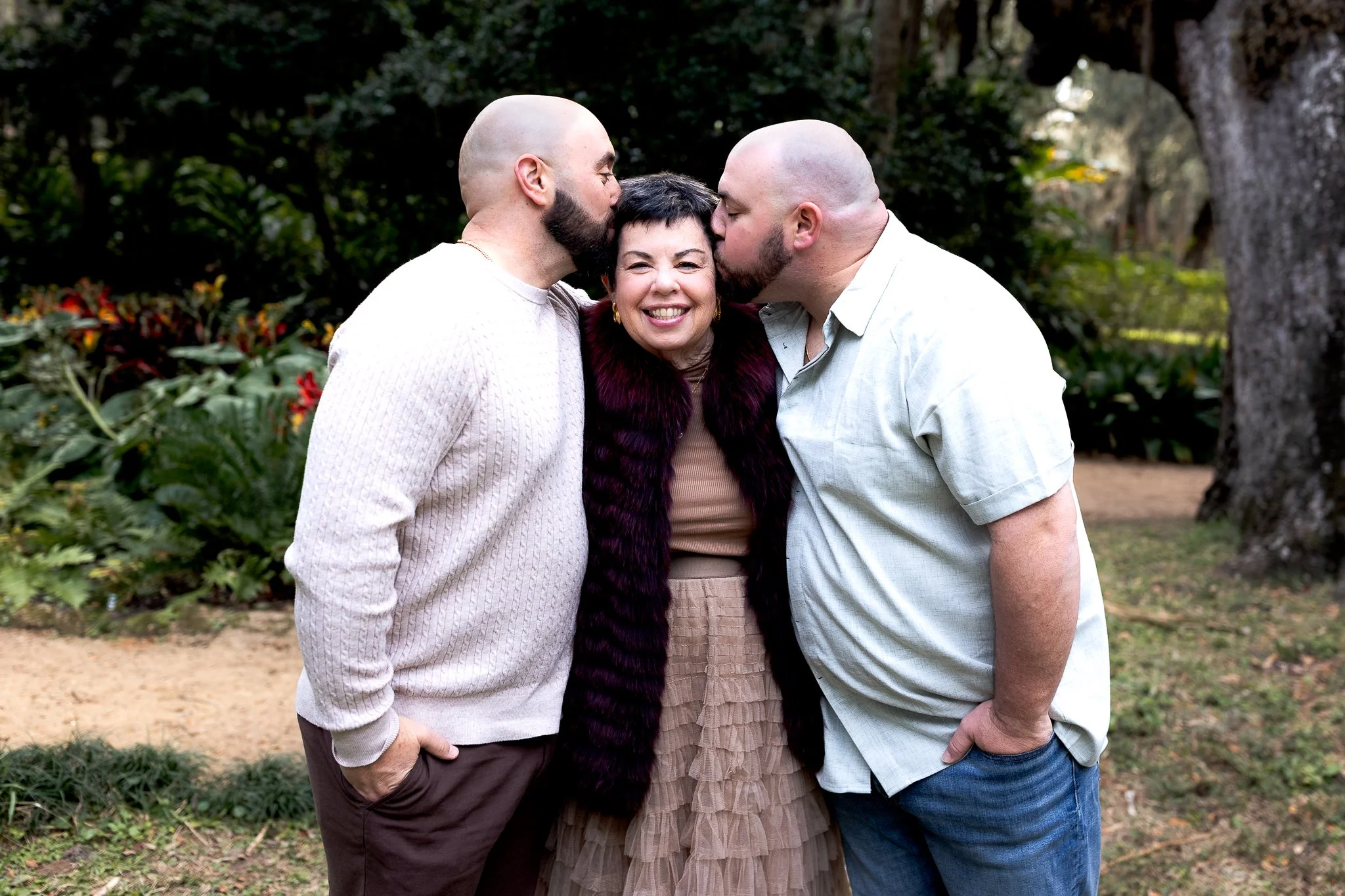 mother with her adult sons who are kissing her and she is smiling