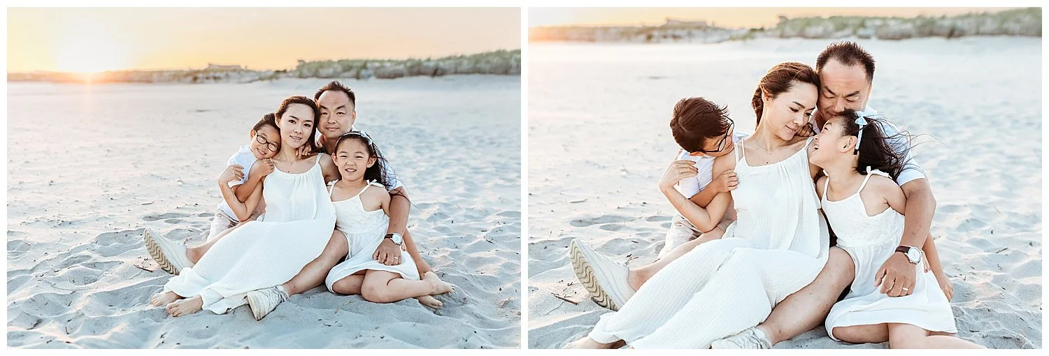 mother and father embracing their children while seated on the sand at sunset