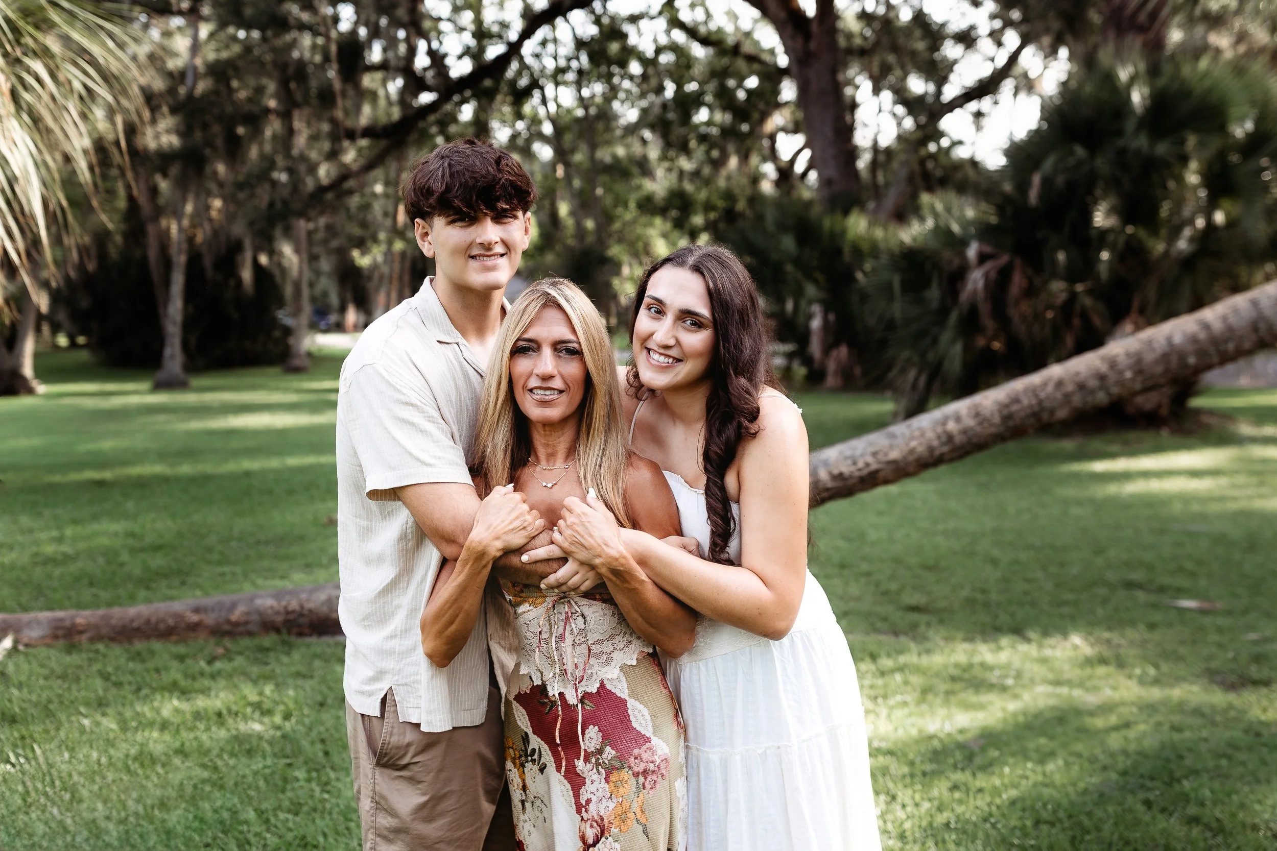 adult children embracing mom in front of palm trees in Atlantic beach for family photos