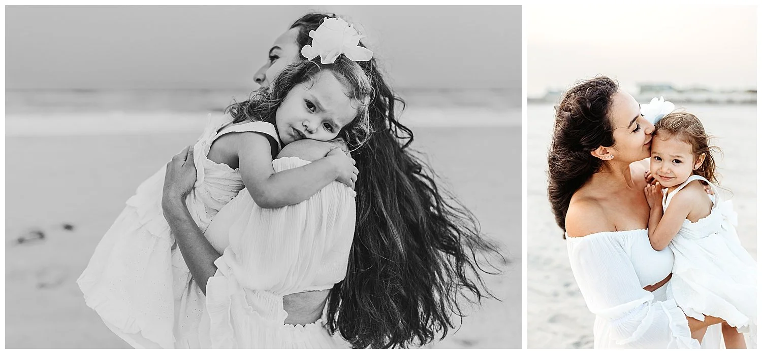 toddler girl embracing mom and smiling while she lays on her shoulder moms hair flowing in wind on beach sunset