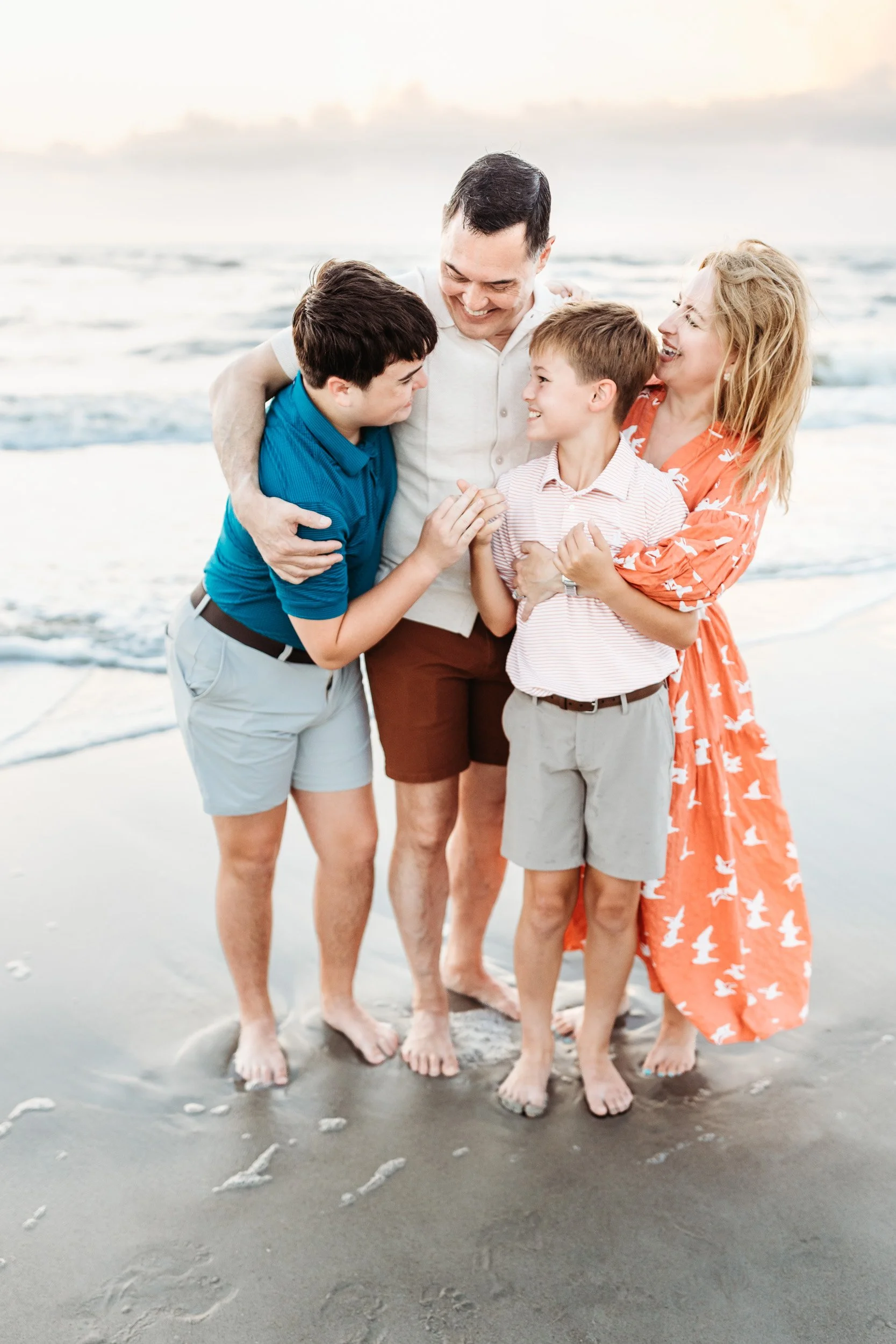 parents hugging their teen and tween sons on the beach in Ponte Vedra for sunrise family photos