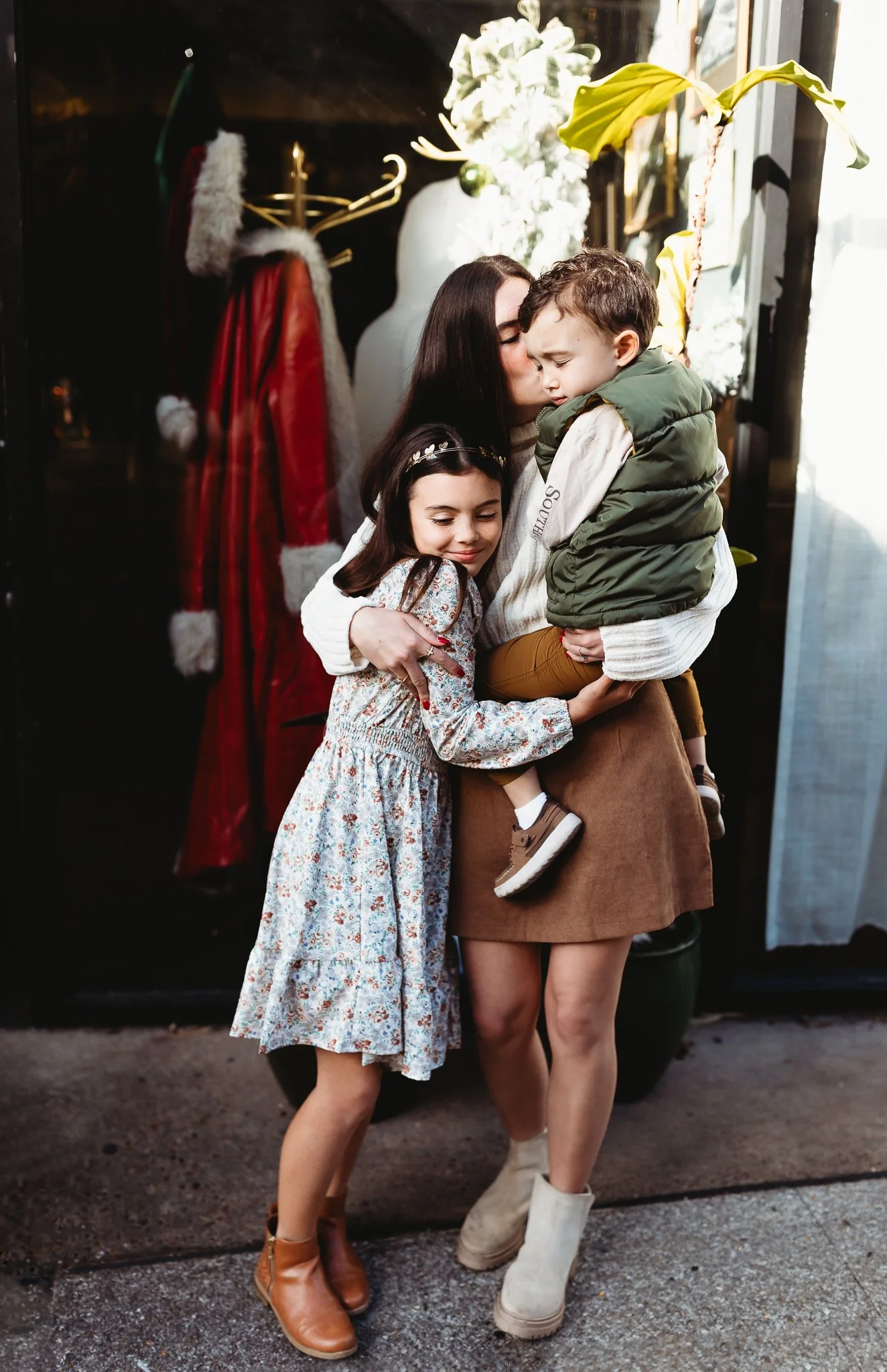 siblings embraced in front of a store window with a Santa coat in st augustine