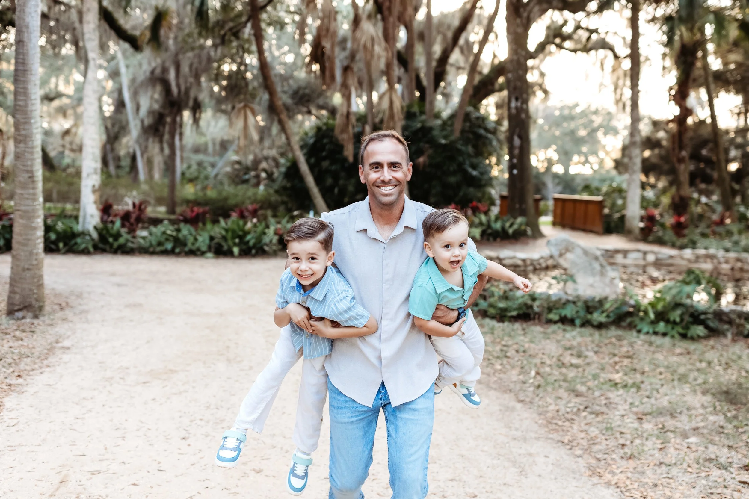 ad at the Washington oaks state garden for family photos running with his boys under his arms and they are all laughing