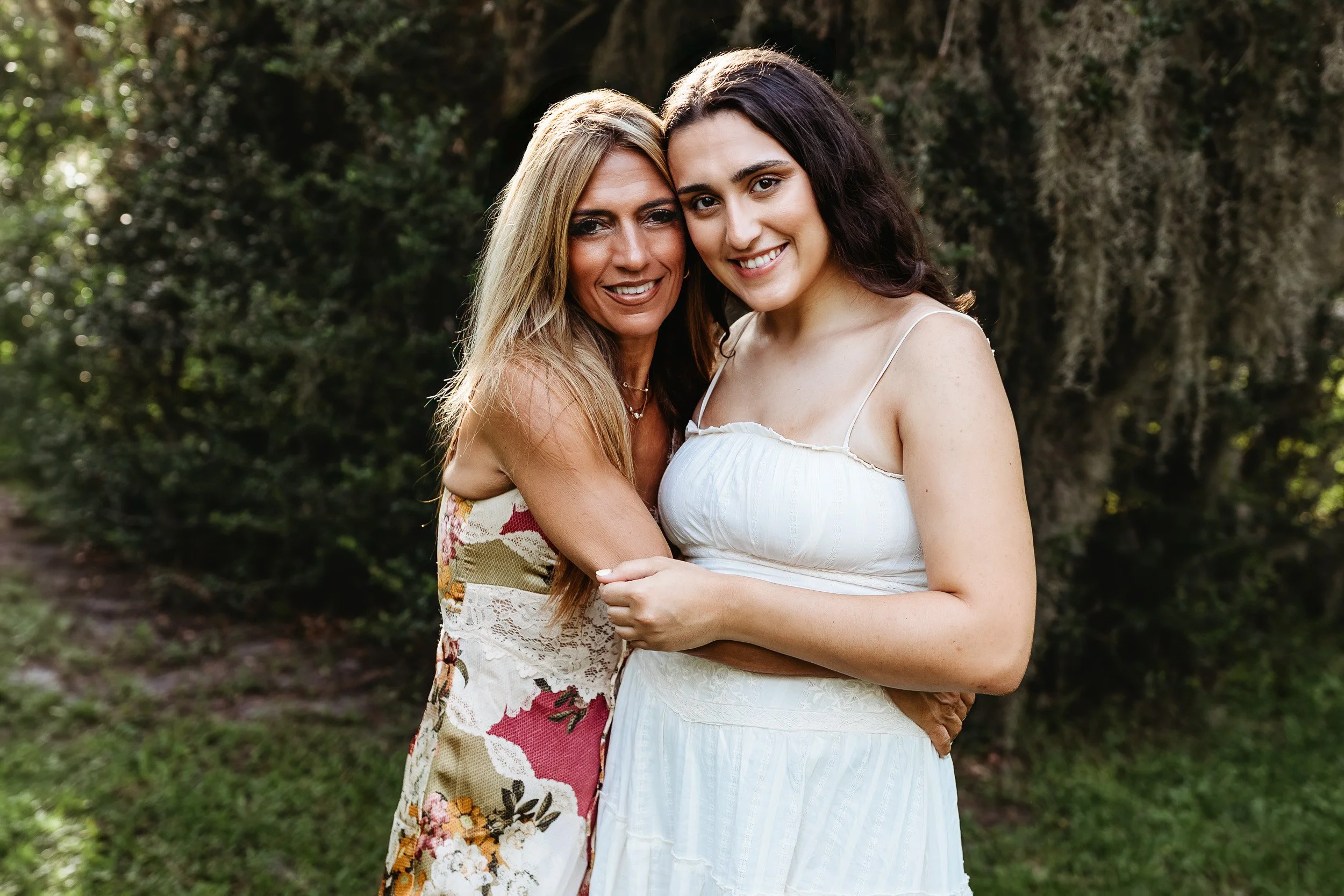 mother with her adult daughter embraced in front of Spanish moss in a park in Atlantic beach