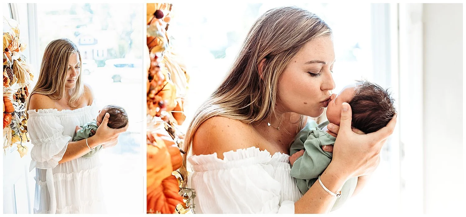 close up of mom kissing baby boy in front of glass door with Fall wreath mom in boho white maxi dress