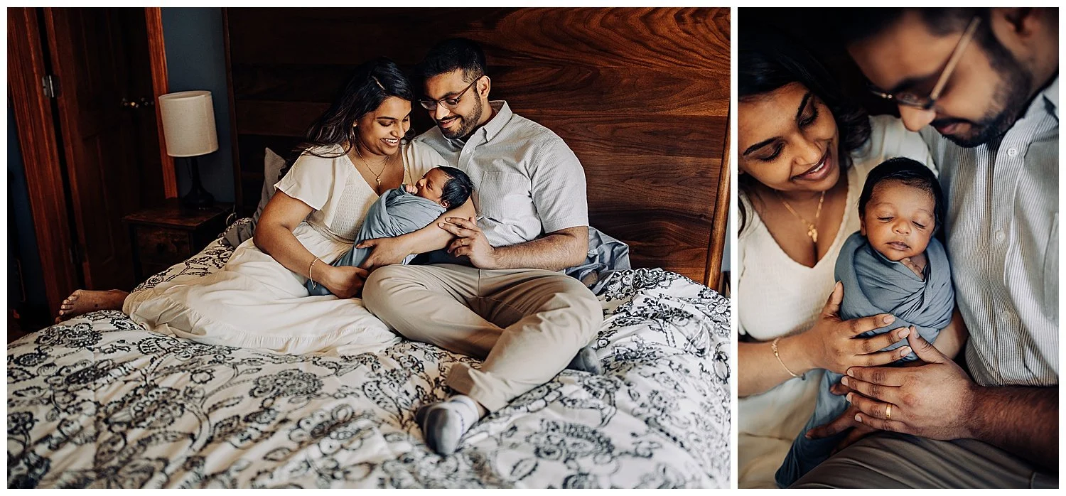 family seated on a bed holding a newborn boy who is swaddled in a light blue blanket and they are looking at him and smiling