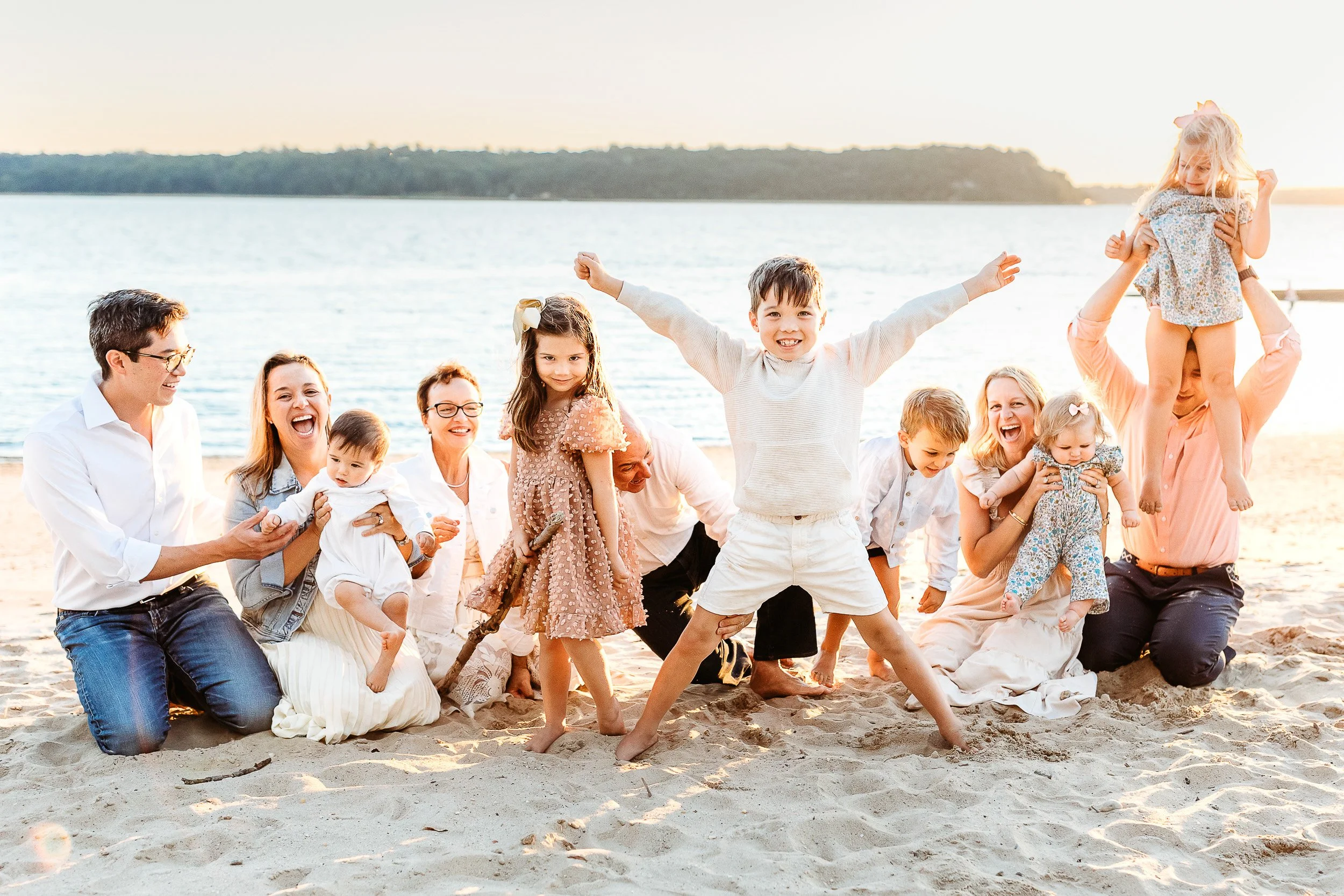 candid family moment during a family photo session with children being silly and dad lifting daughter in the air.  the rest of the family is laughing.  
