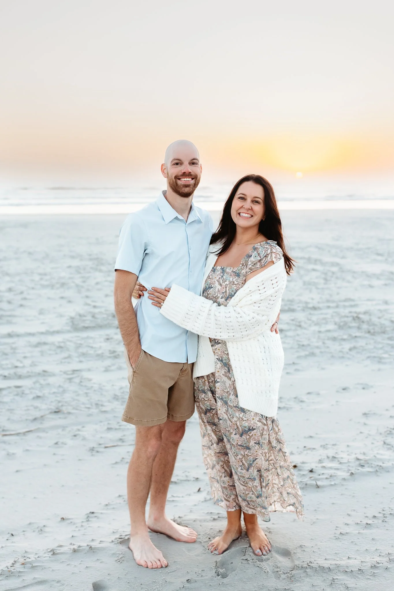 Couple standing on Crescent Beach at sunrise during a soft, golden morning photography session.