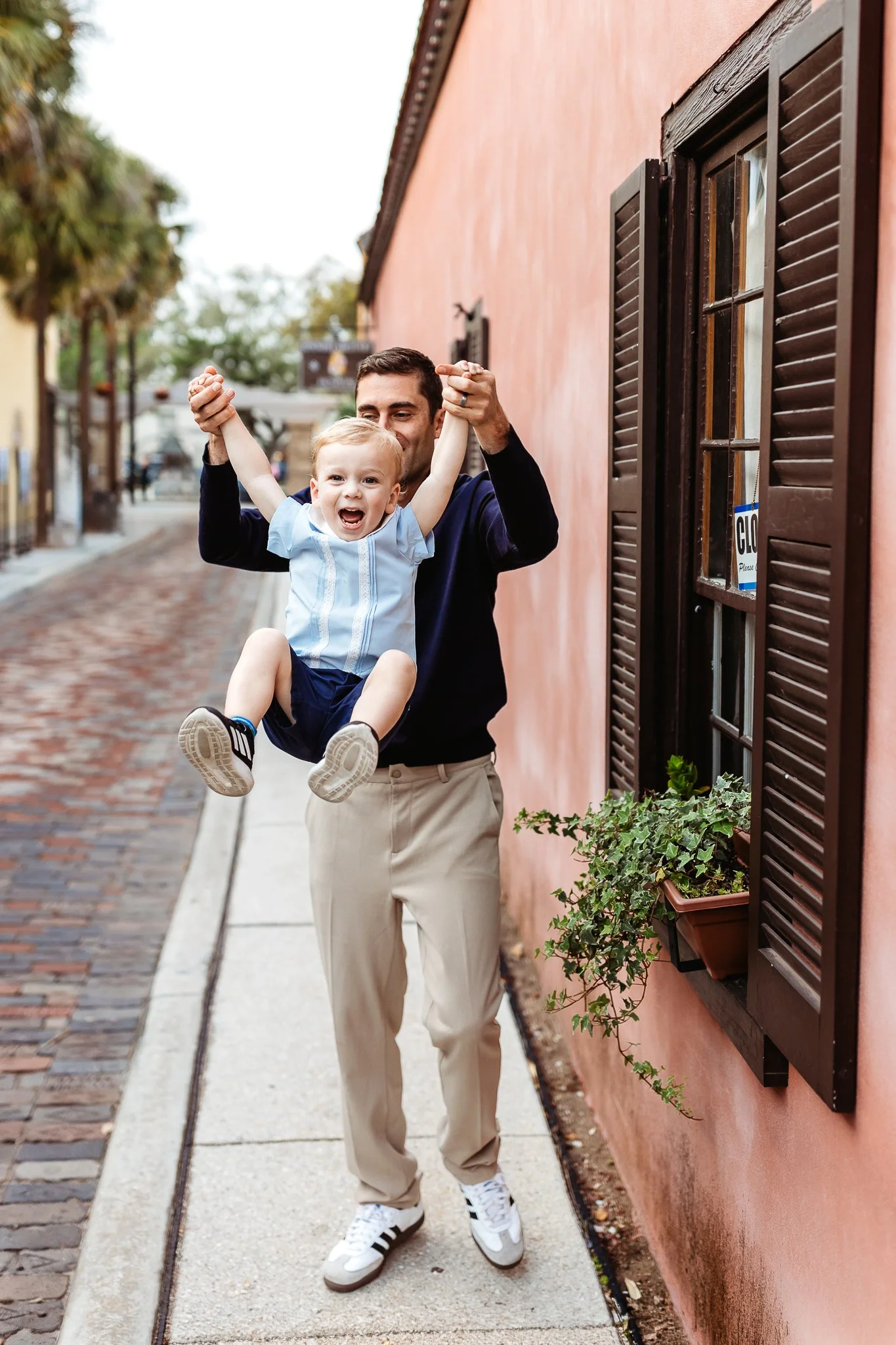 dad swinging son on a cobblestone street during family photos