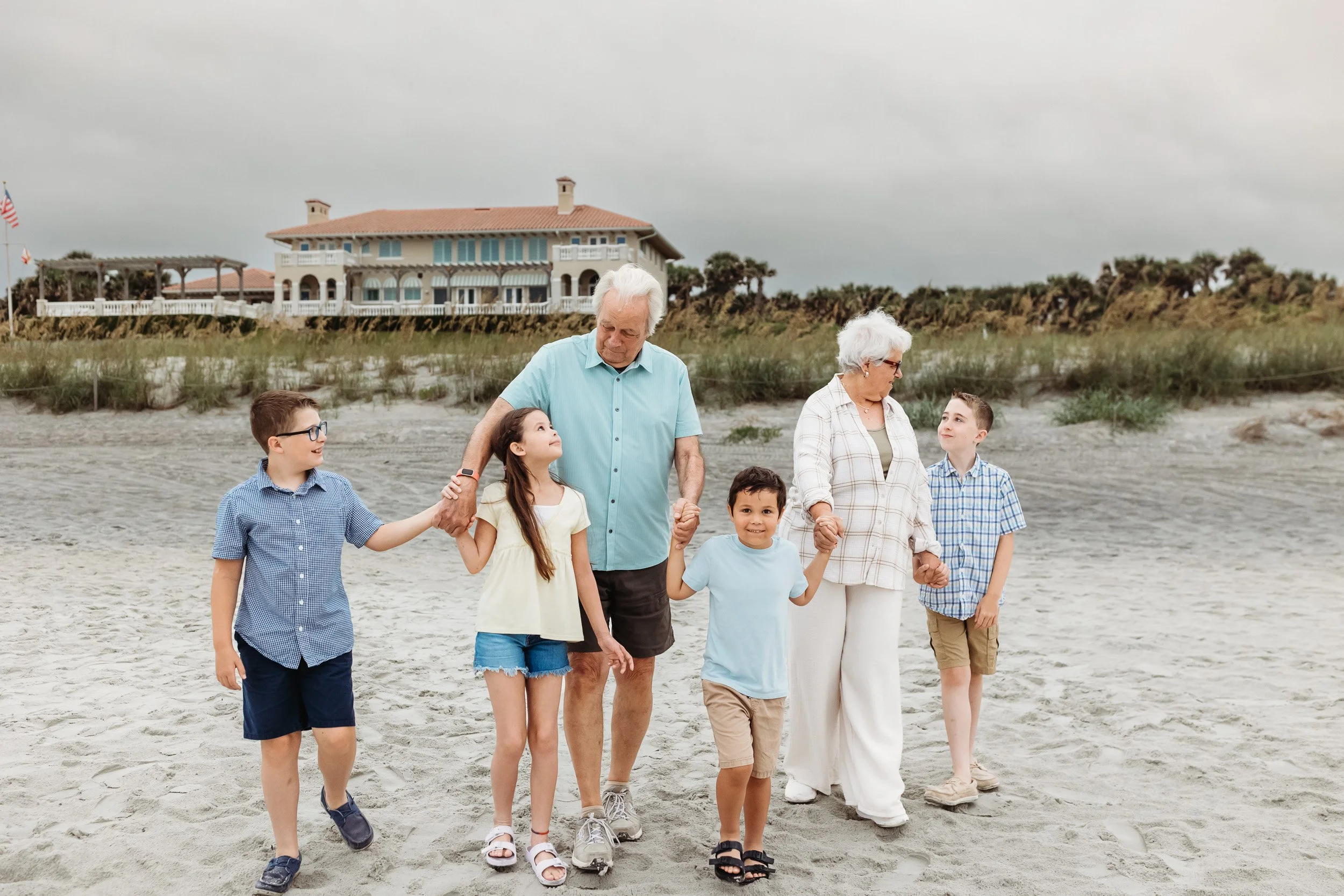 grandparents walking on the beach at sunrise hand in hand with their grandchildren