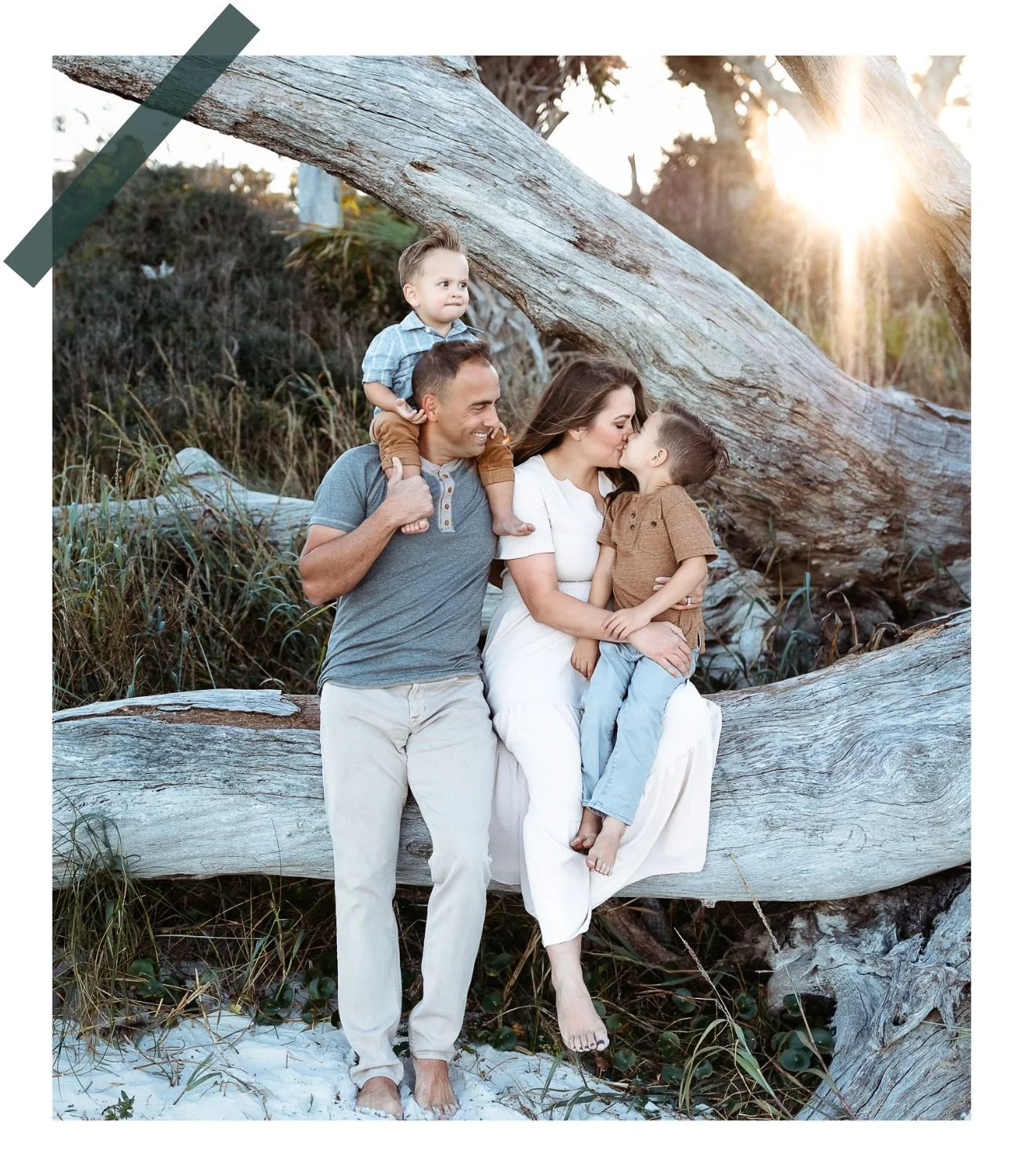 family at th beach at sunset and mom is kissing son and dad watching with toddler on shoulders they are having a sunset family photo session taken