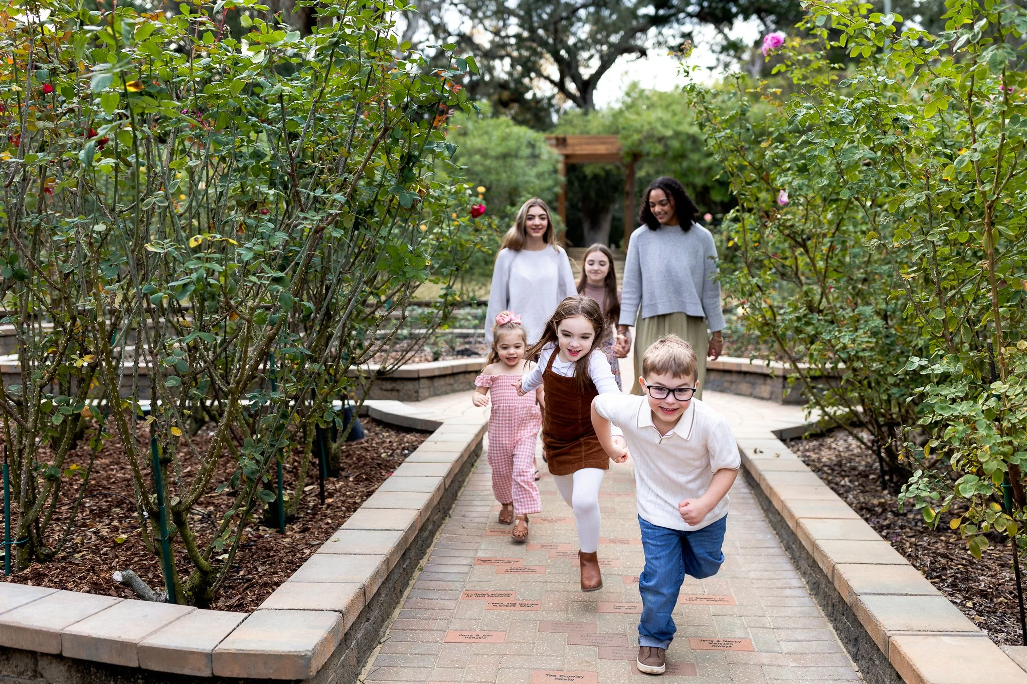 cousins running along a path away from the rose garden in Washington oaks park
